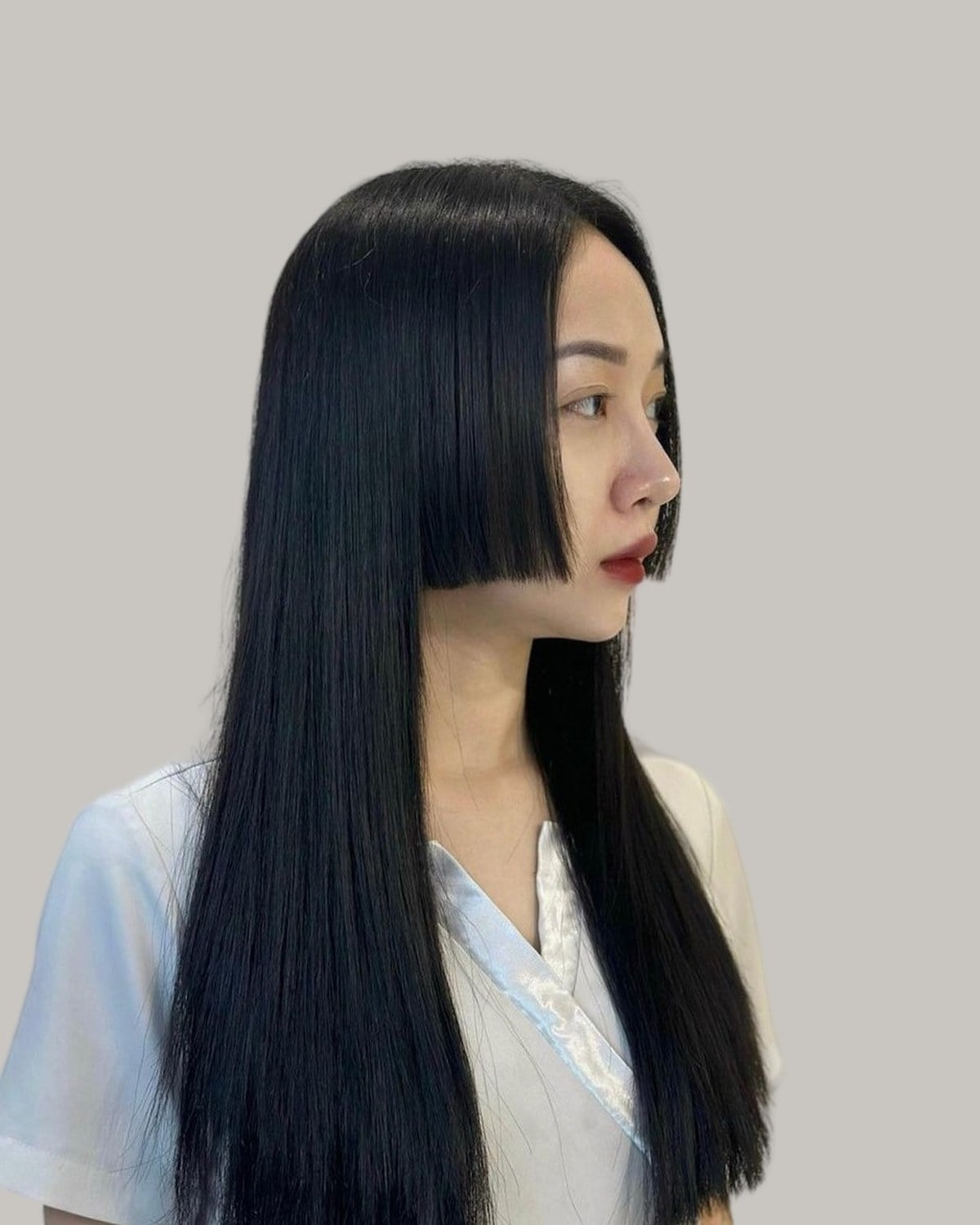 Woman with long, straight black hair and a blunt side panel, seen in profile
