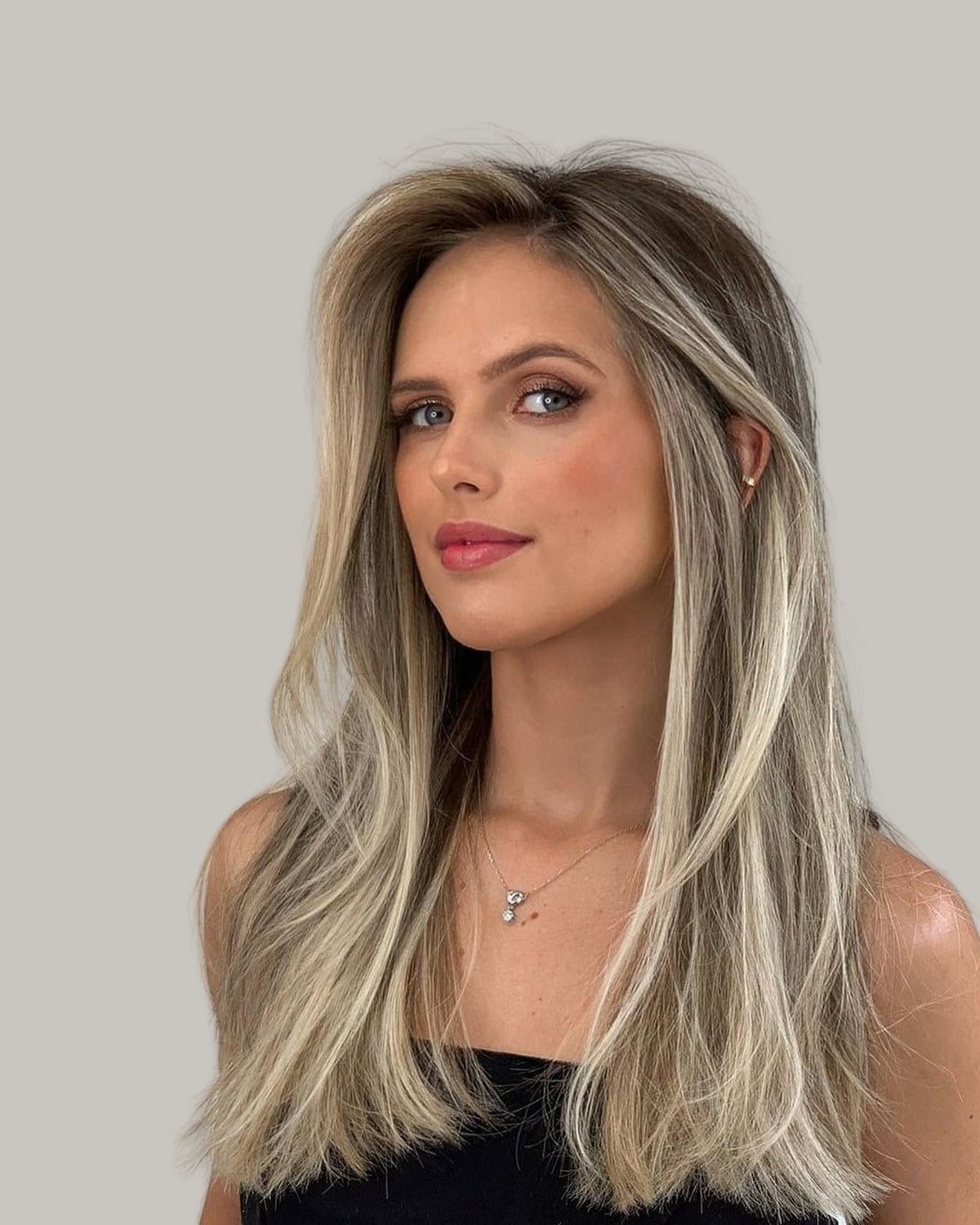 Woman with long, fine blonde hair with darker roots, in a black top