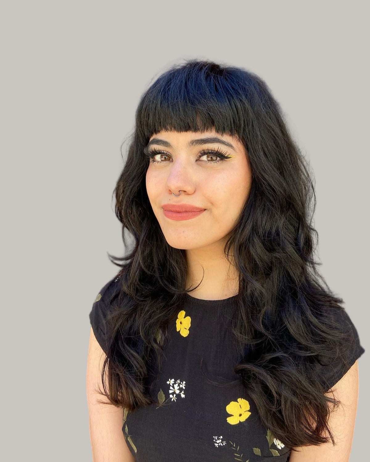 Smiling woman with long black waves and short blunt bangs