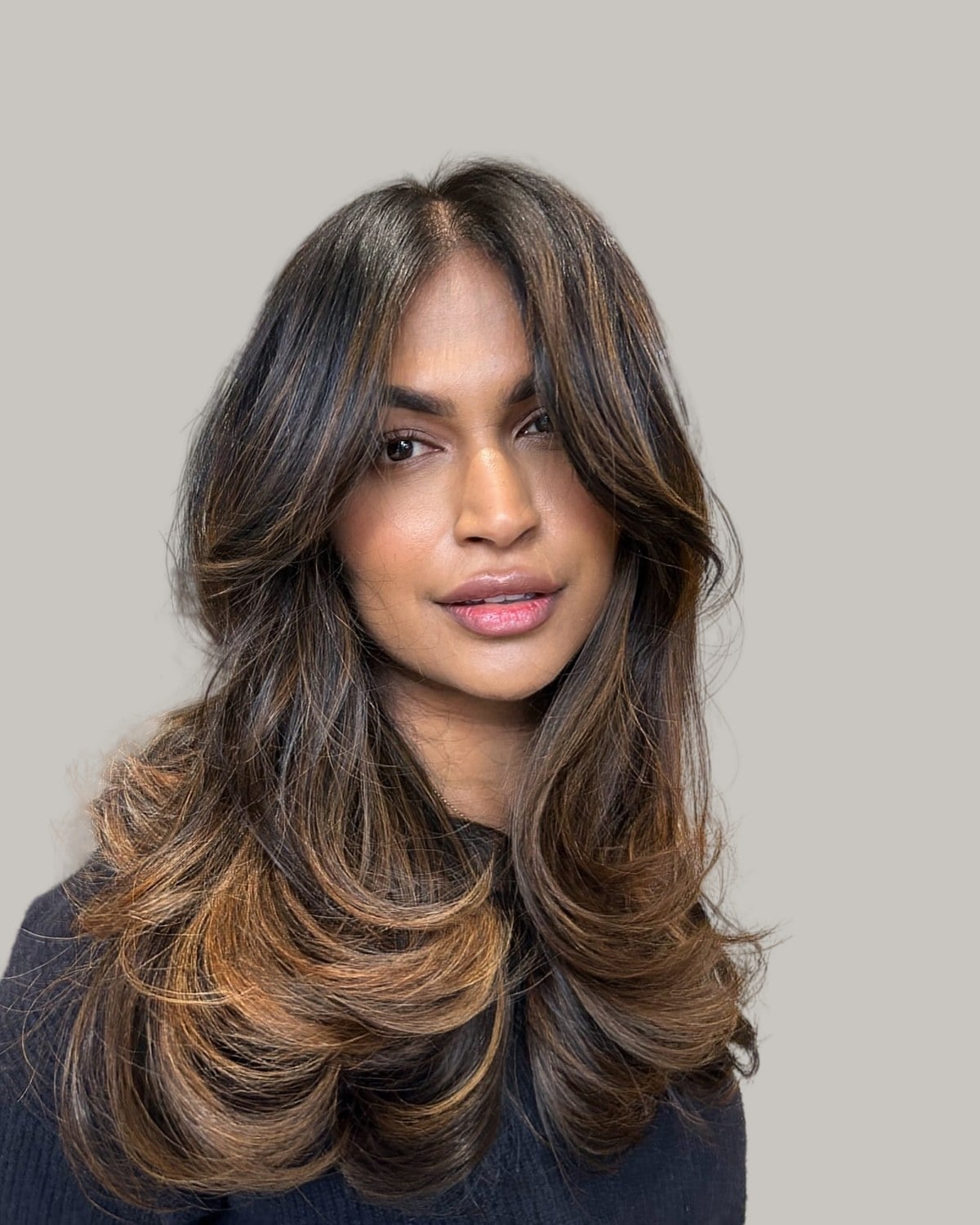 Woman with long dark hair, caramel ends and short layers around her face
