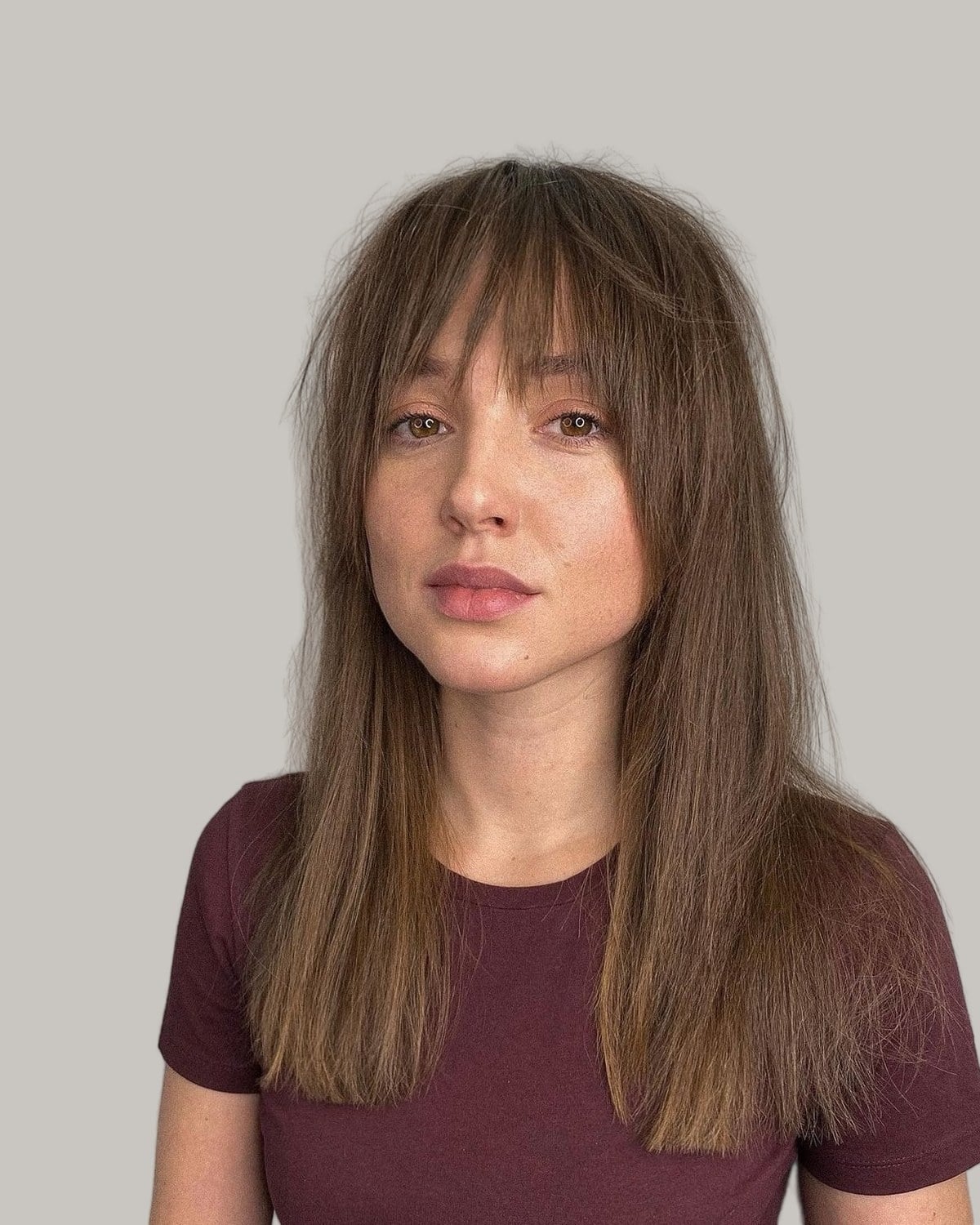 Woman with long, straight brown hair and a full fringe