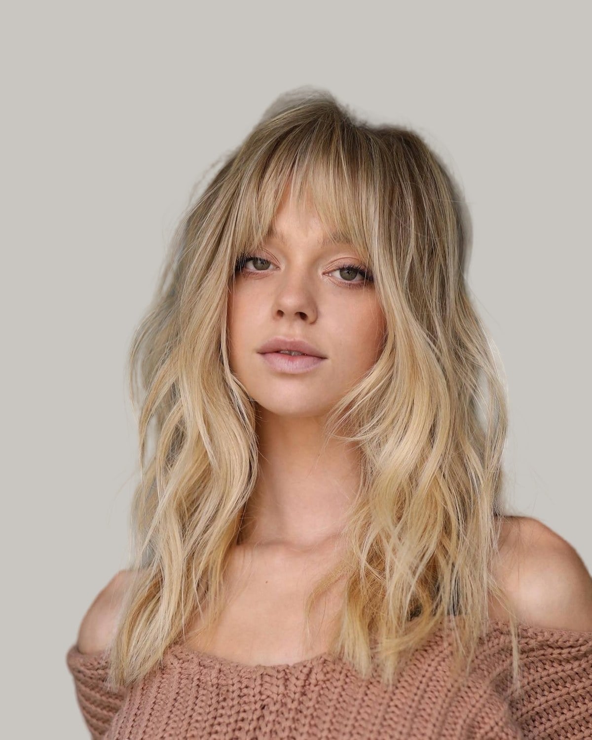 Woman with long blonde waves and light, wispy bangs