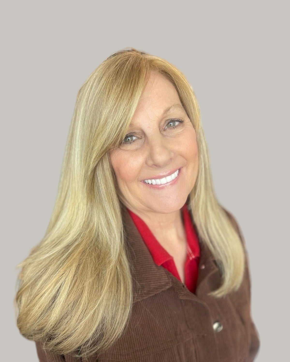 Smiling older woman with long, straight blonde hair and side-swept bangs