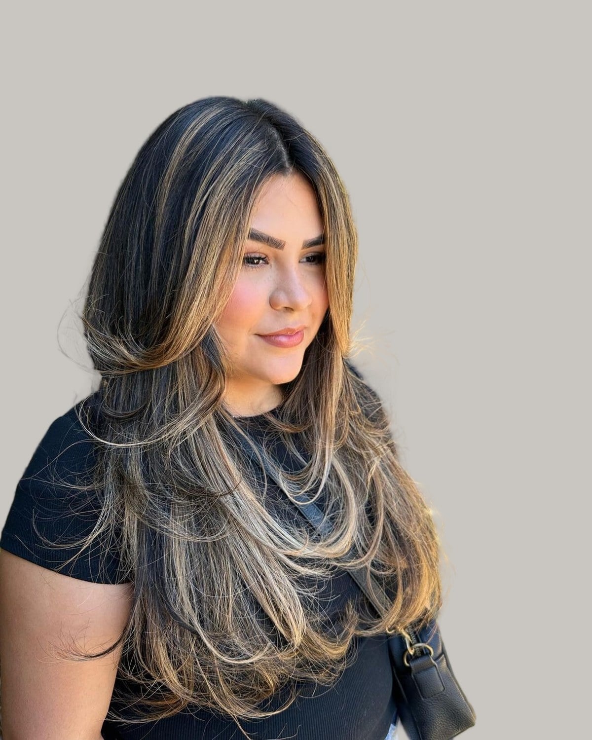 Woman with long black hair and blonde layers, seen in three-quarter view