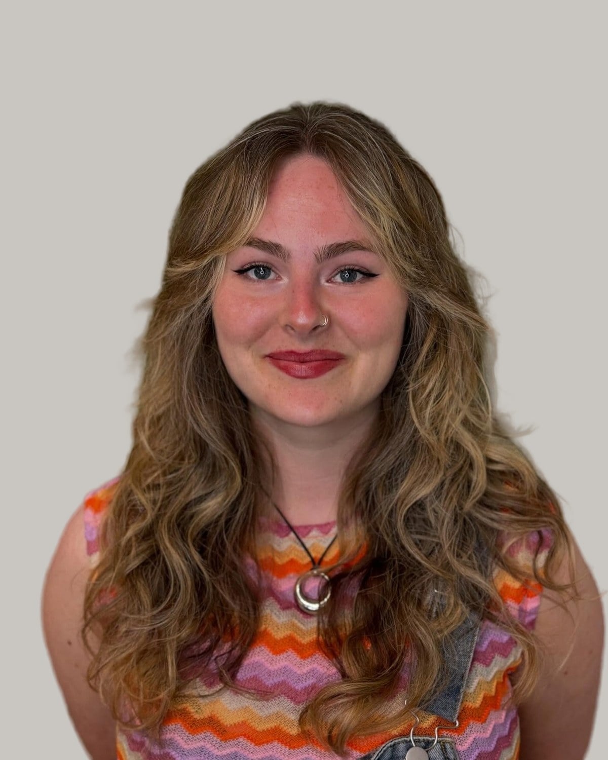 Smiling woman with a round face and long, wavy, highlighted hair