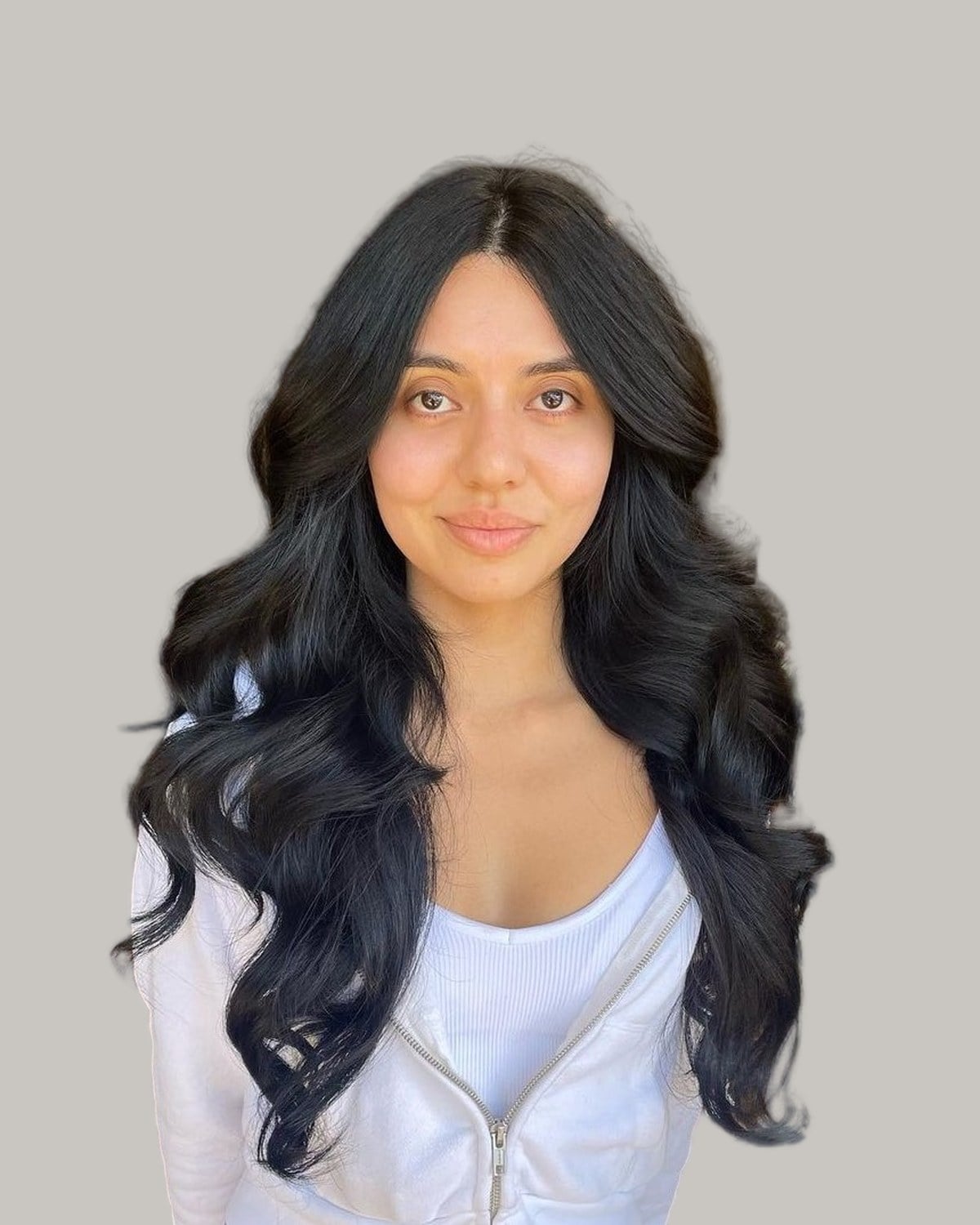Woman with long black hair in big, loose waves and a center part
