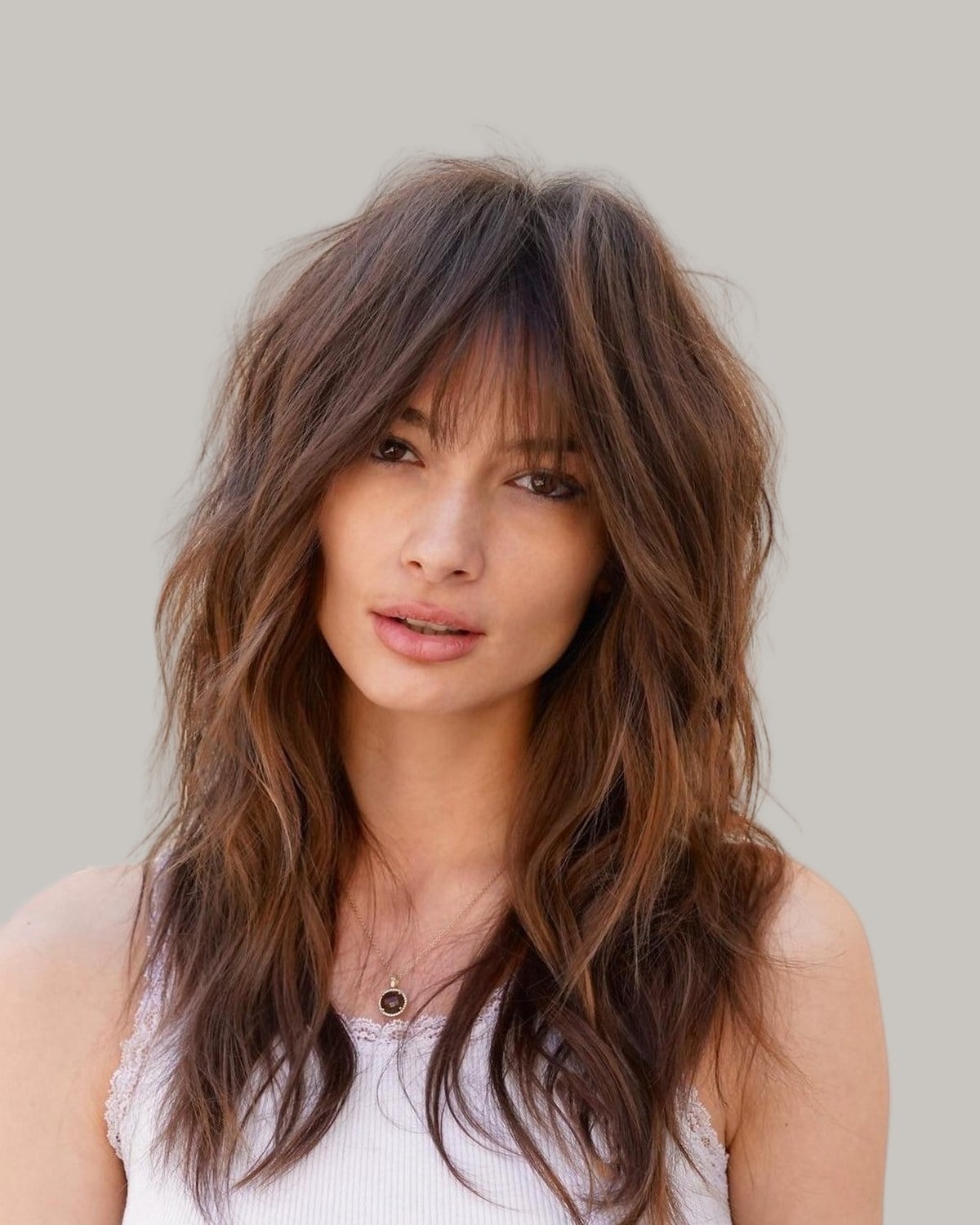 Woman with a long brunette shag and wispy bangs