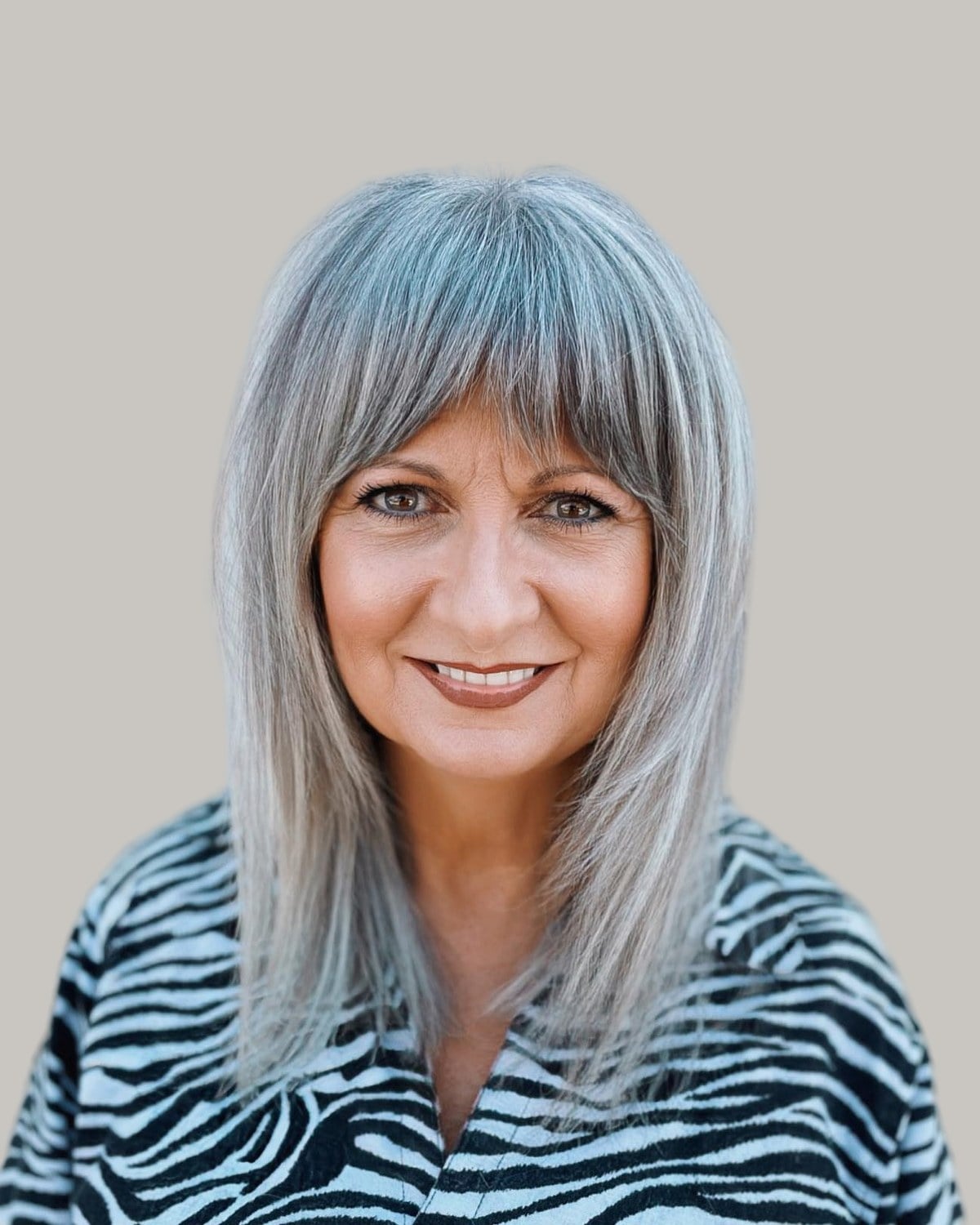 Smiling older woman with long, straight silver hair and bangs