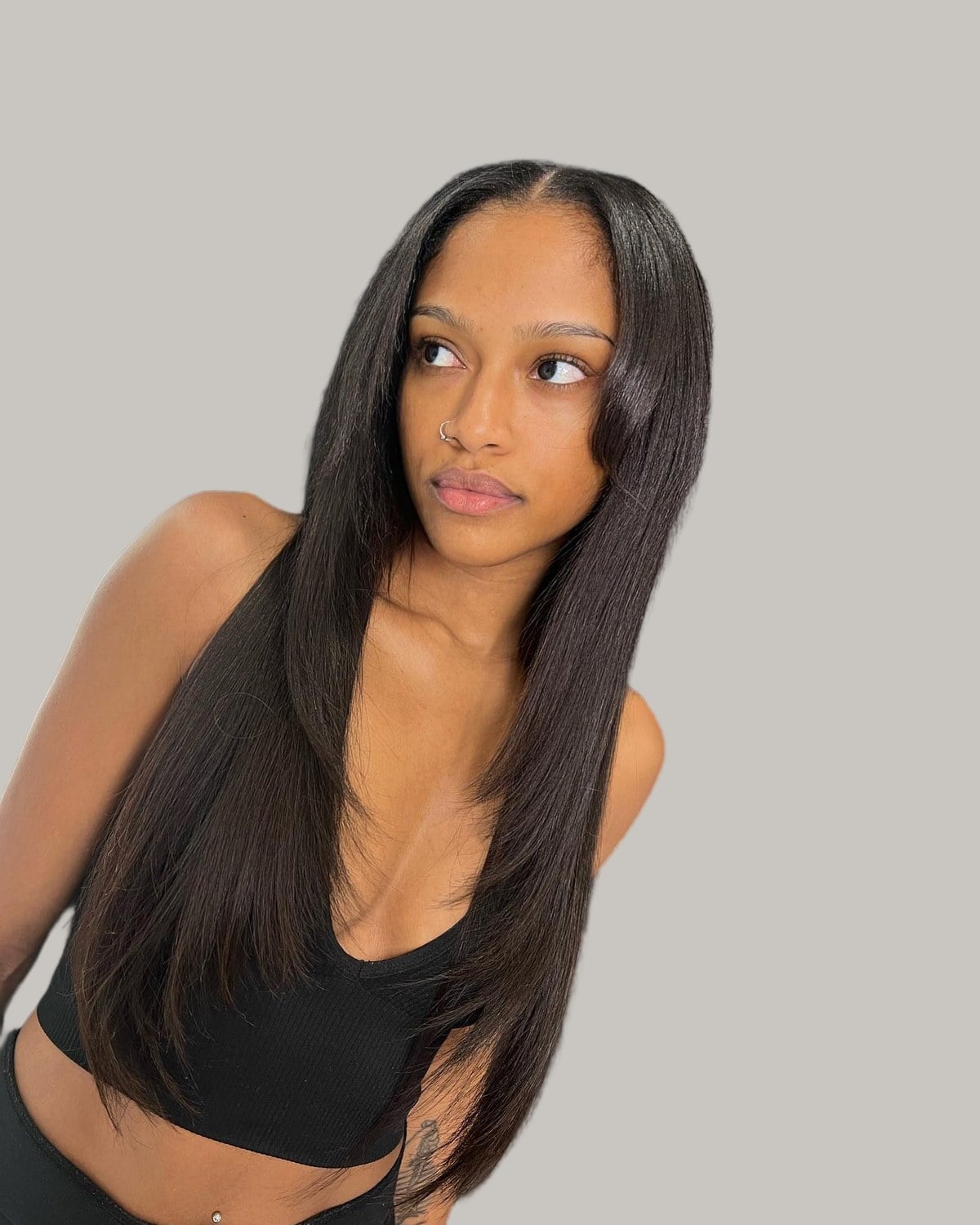 Woman with a long, sleek silk press and a center part, looking to the side