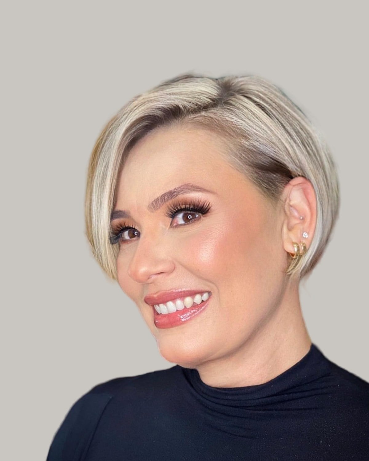 Smiling woman with a platinum bixie tucked behind one ear