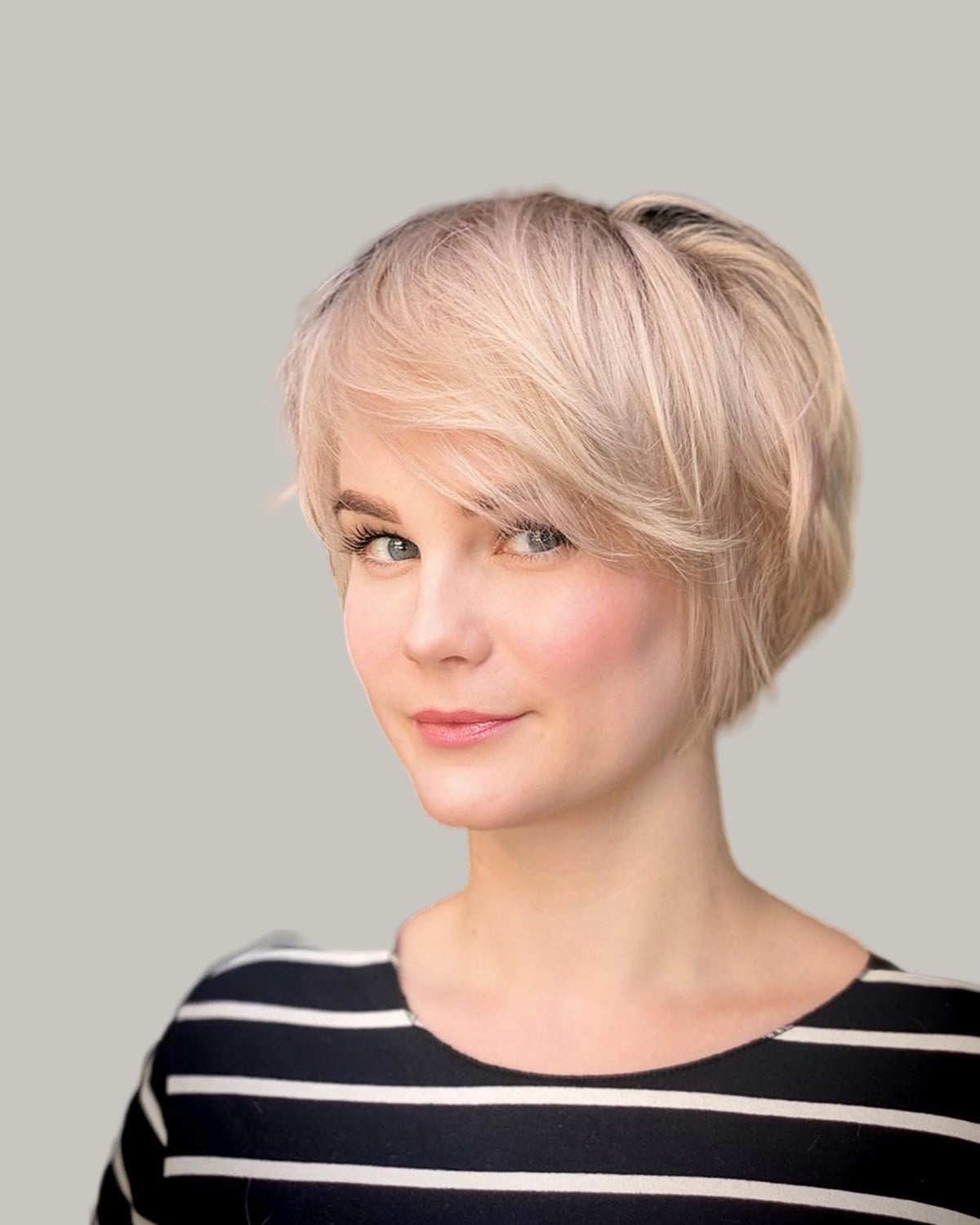 Woman with a pale blonde bixie and a long side-swept fringe, in a striped top