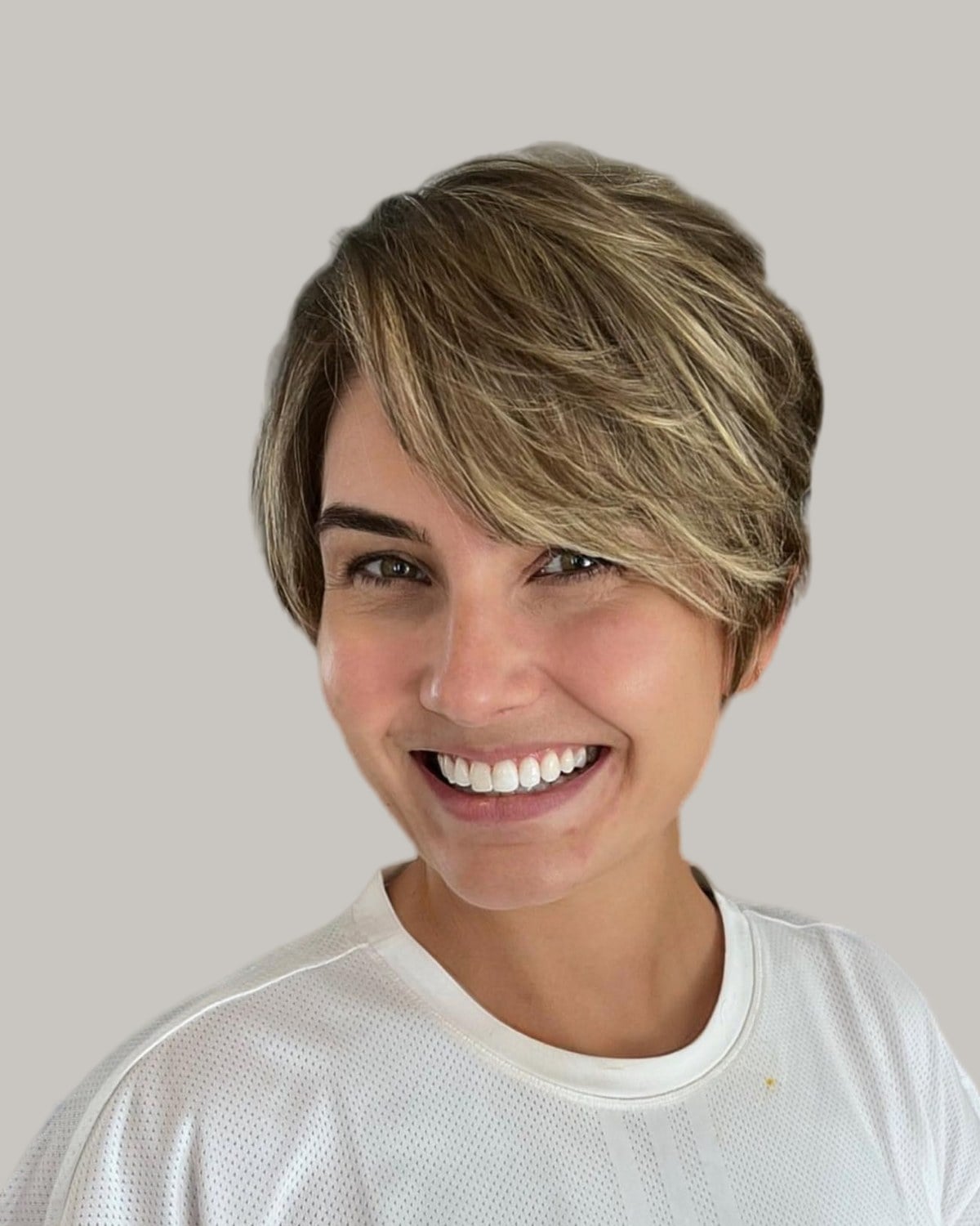 Smiling woman with a highlighted pixie and long feathered bangs