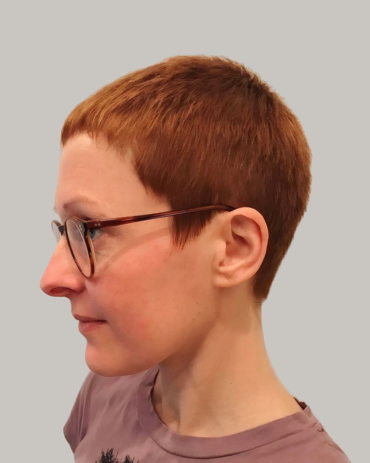 Woman with a very short copper pixie and glasses, in profile