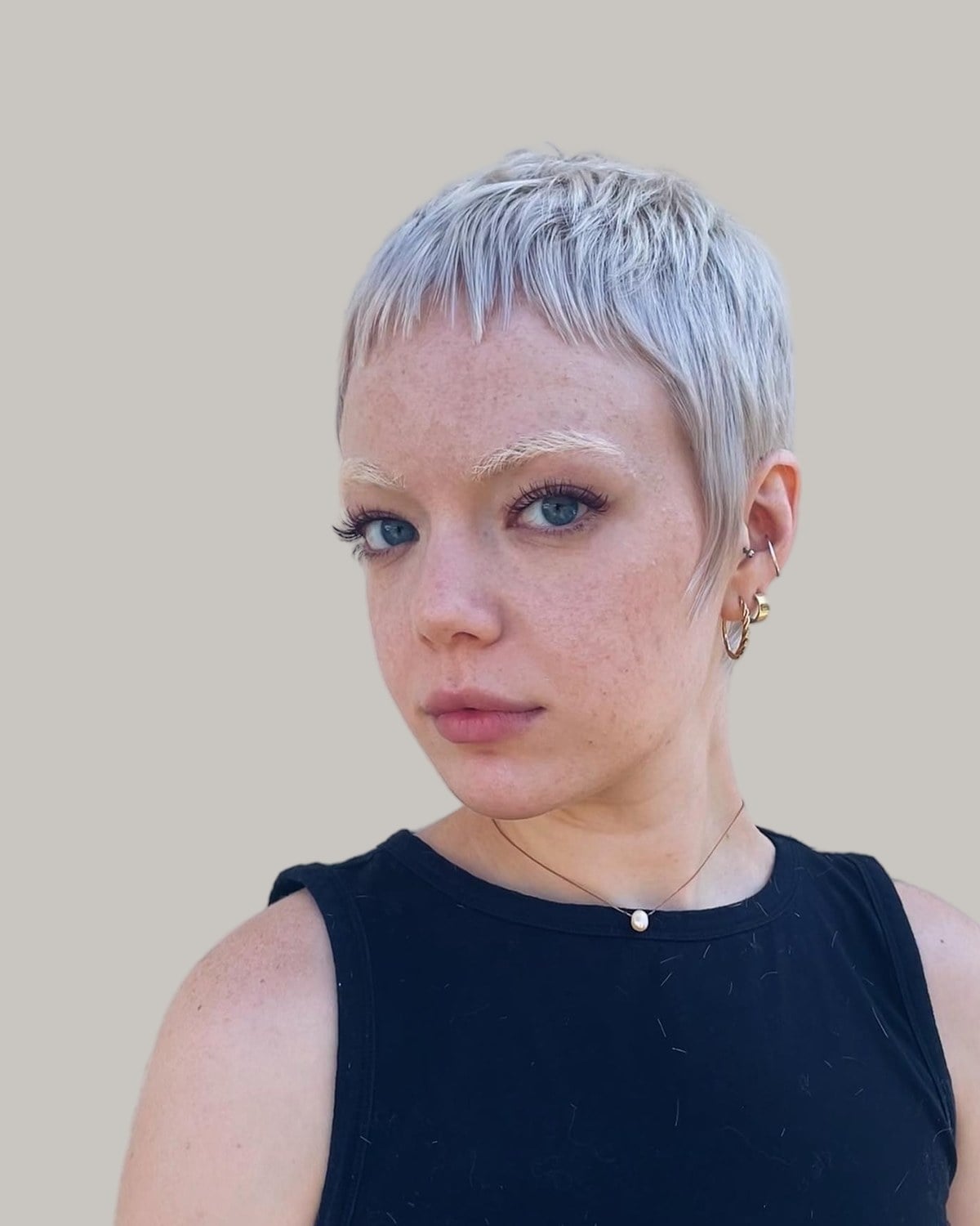 Woman with a cropped platinum pixie and very short bangs
