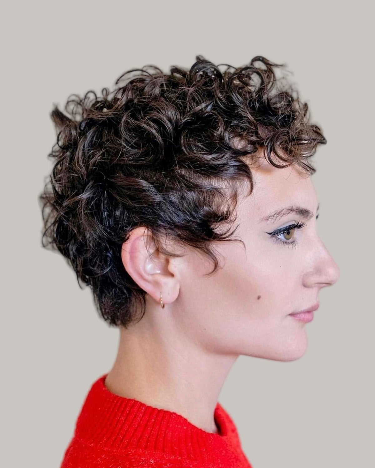 Woman with a curly brown pixie, seen in profile