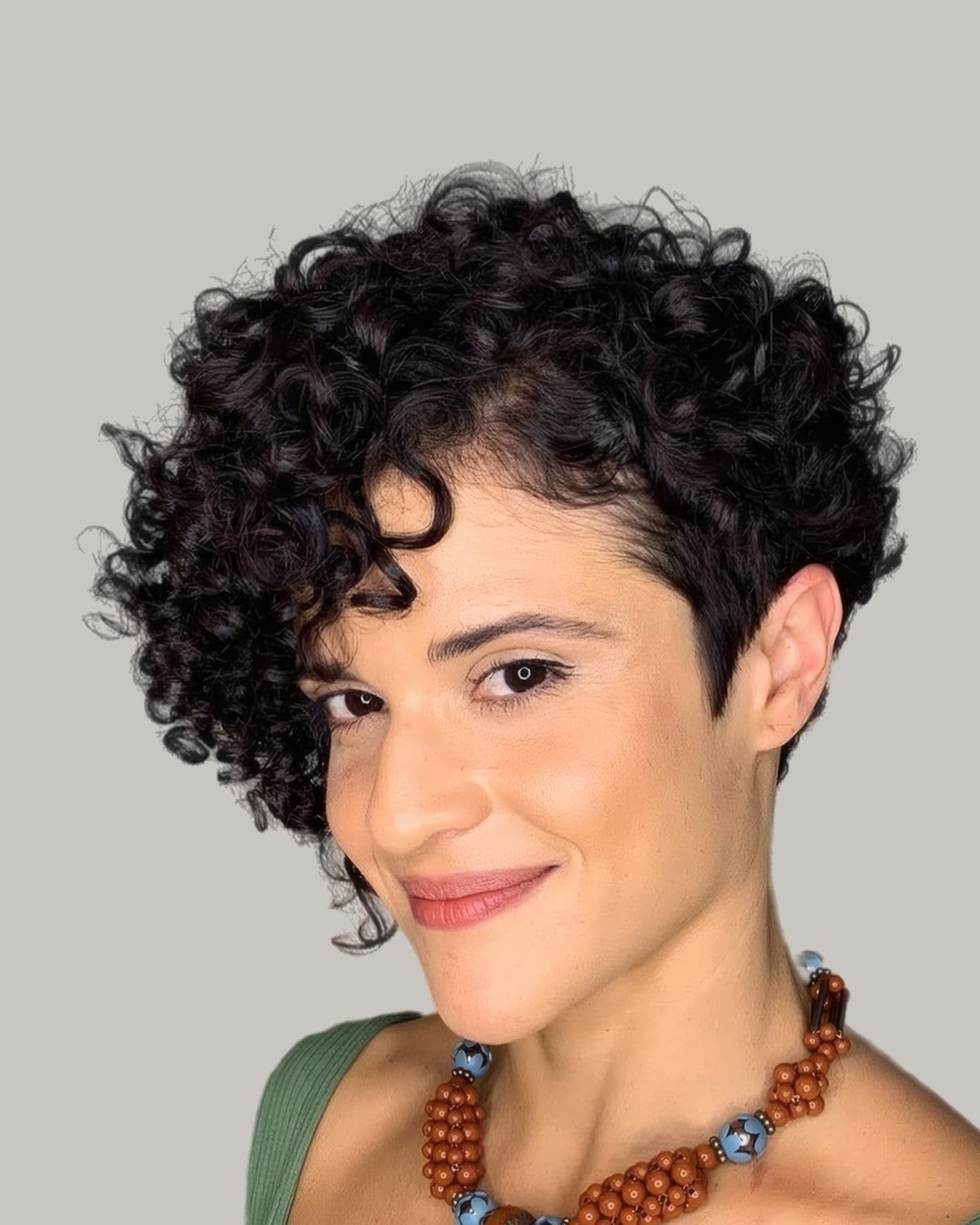 Smiling woman with a black curly pixie and a side fringe