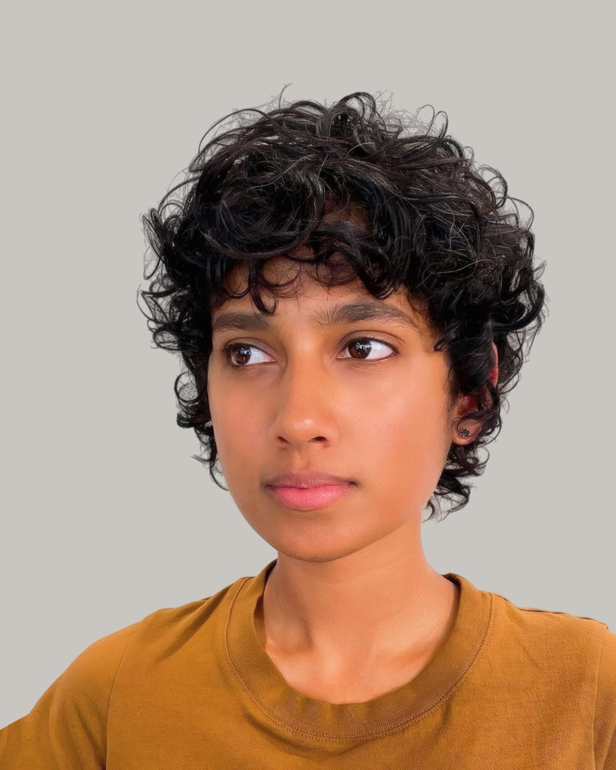 Woman with a curly black shag and curly bangs, looking to the side