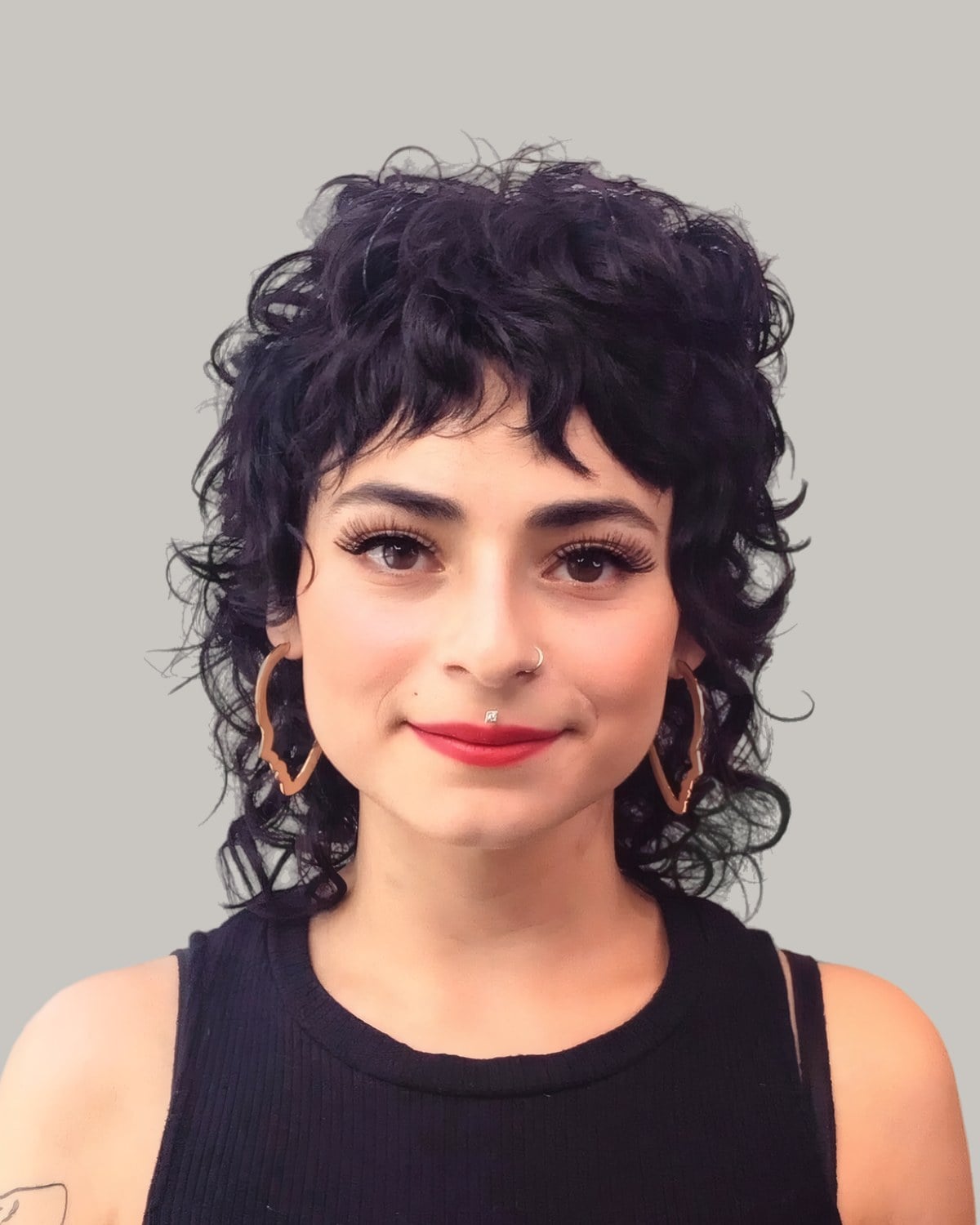 Smiling woman with a black curly wolf cut and curly bangs
