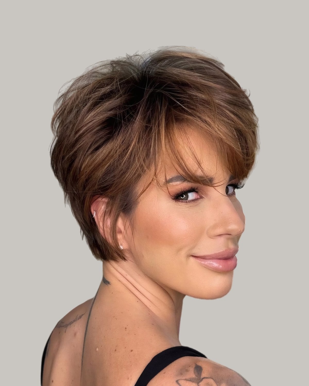 Woman with a brown feathered pixie and swept bangs, looking back