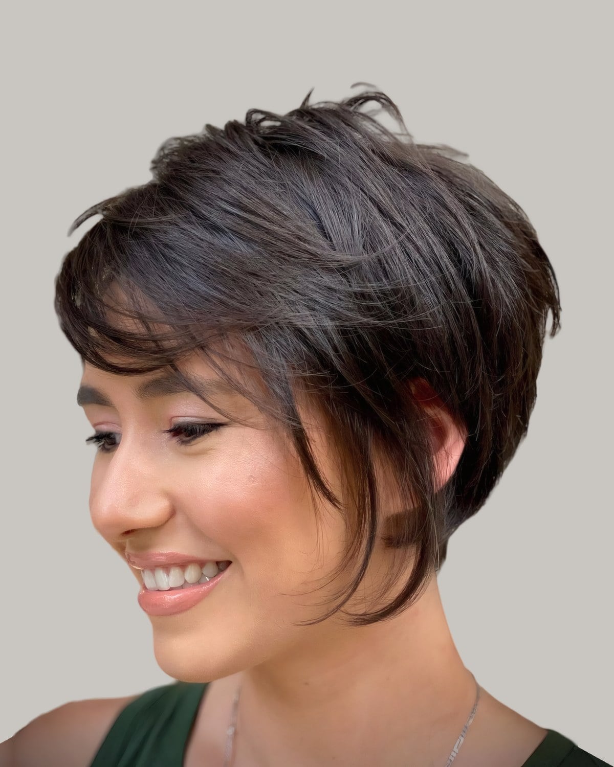 Smiling woman with a brown feathered short shag and a side fringe