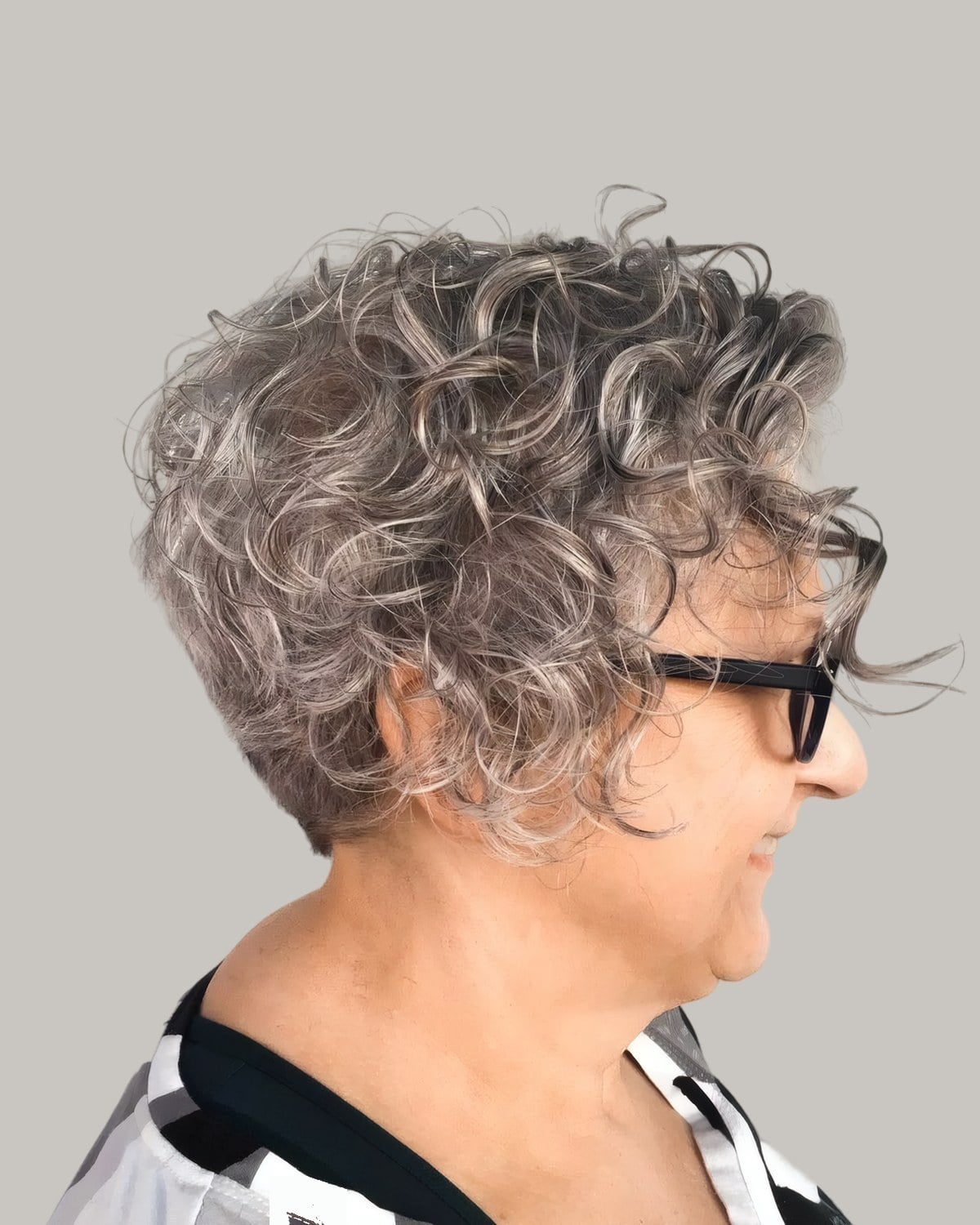 Woman with short gray curls and dark glasses, in profile