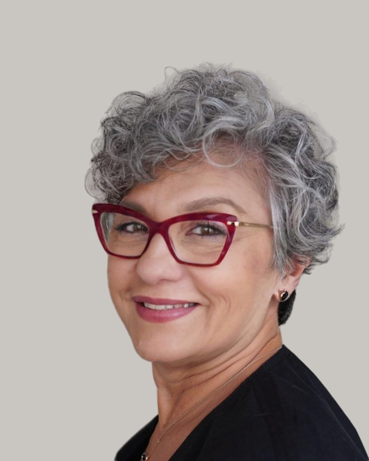 Smiling woman with short gray curls and red glasses