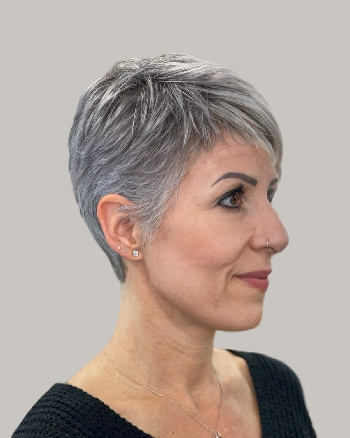 Woman with a gray pixie and a short fringe, seen from the side