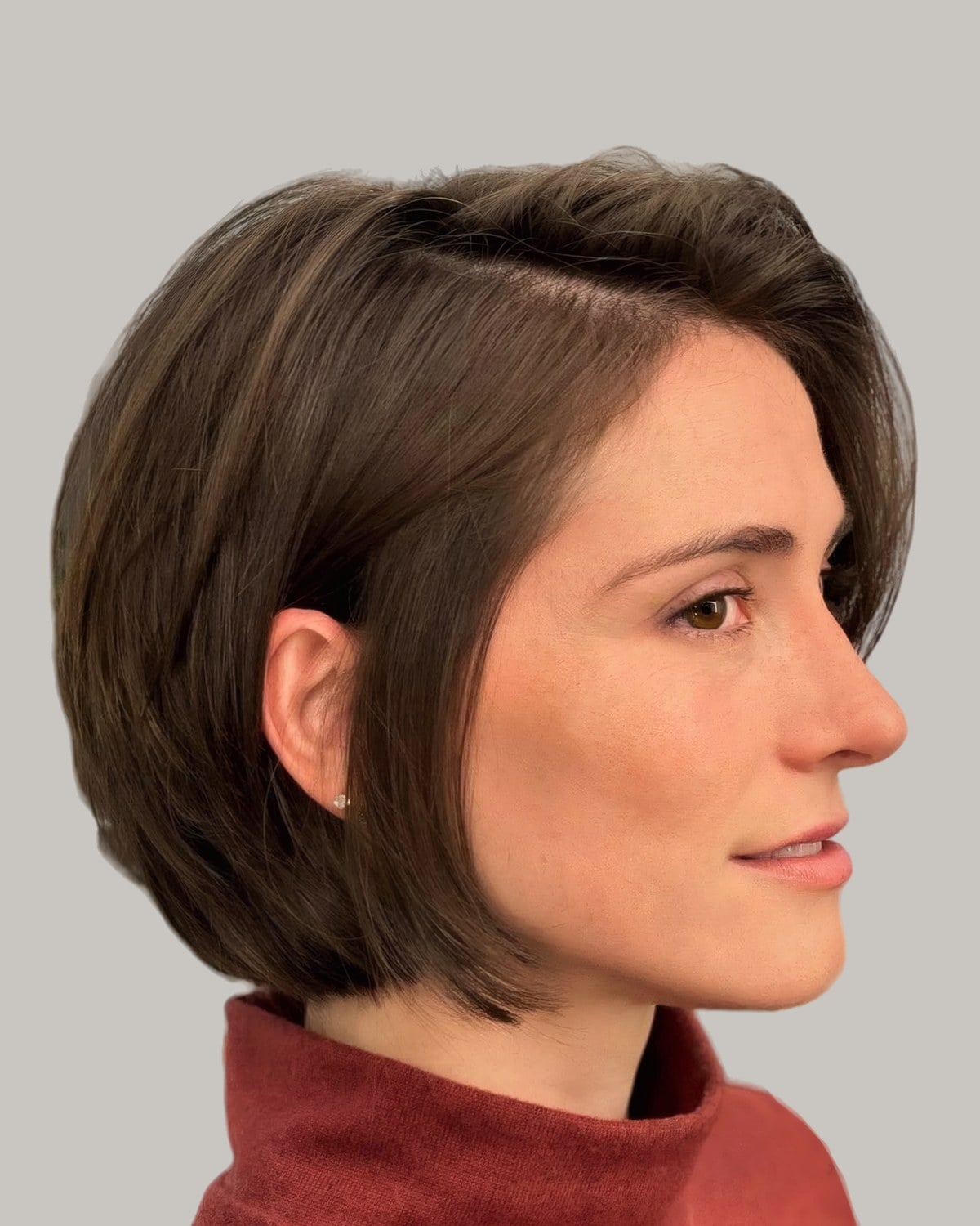 Woman with a brown chin-length bob and a deep side part, in profile