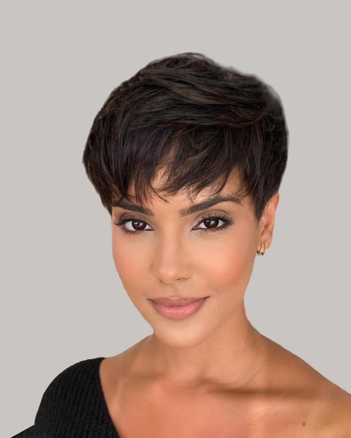 Woman with a dark messy pixie and piecey bangs, facing the camera