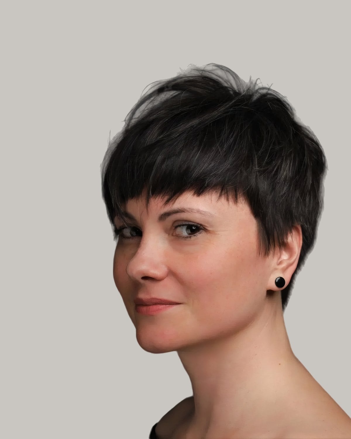 Woman with a black pixie and short choppy bangs, seen at an angle