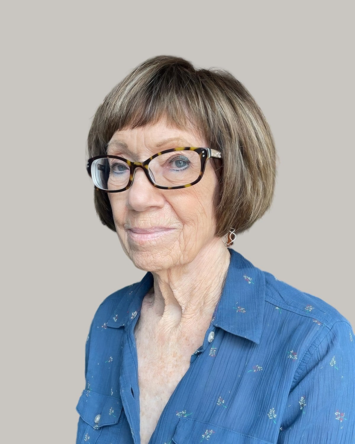 Woman with a light brown blunt bob, full bangs and tortoiseshell glasses