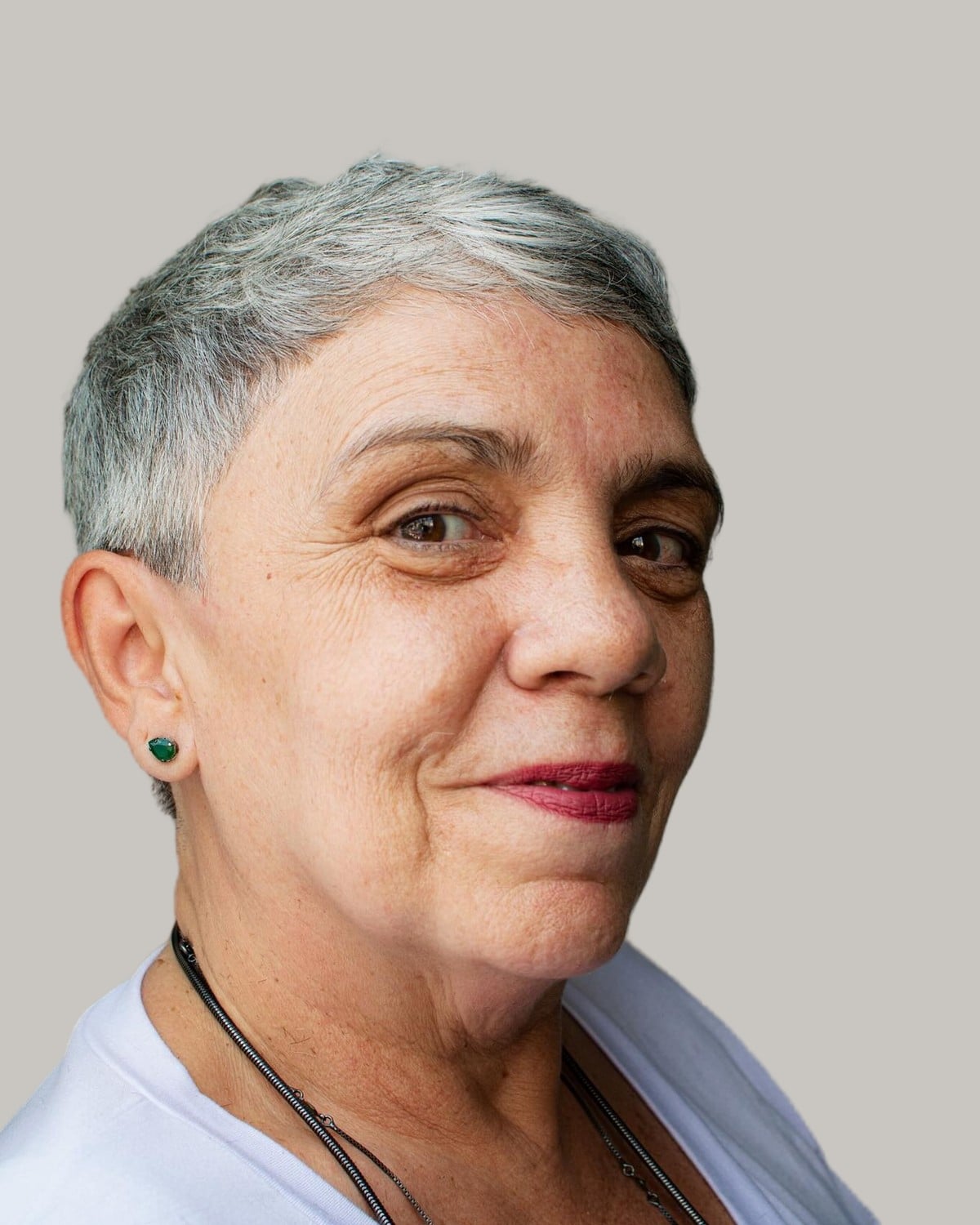Woman with a very short gray pixie and green stud earrings