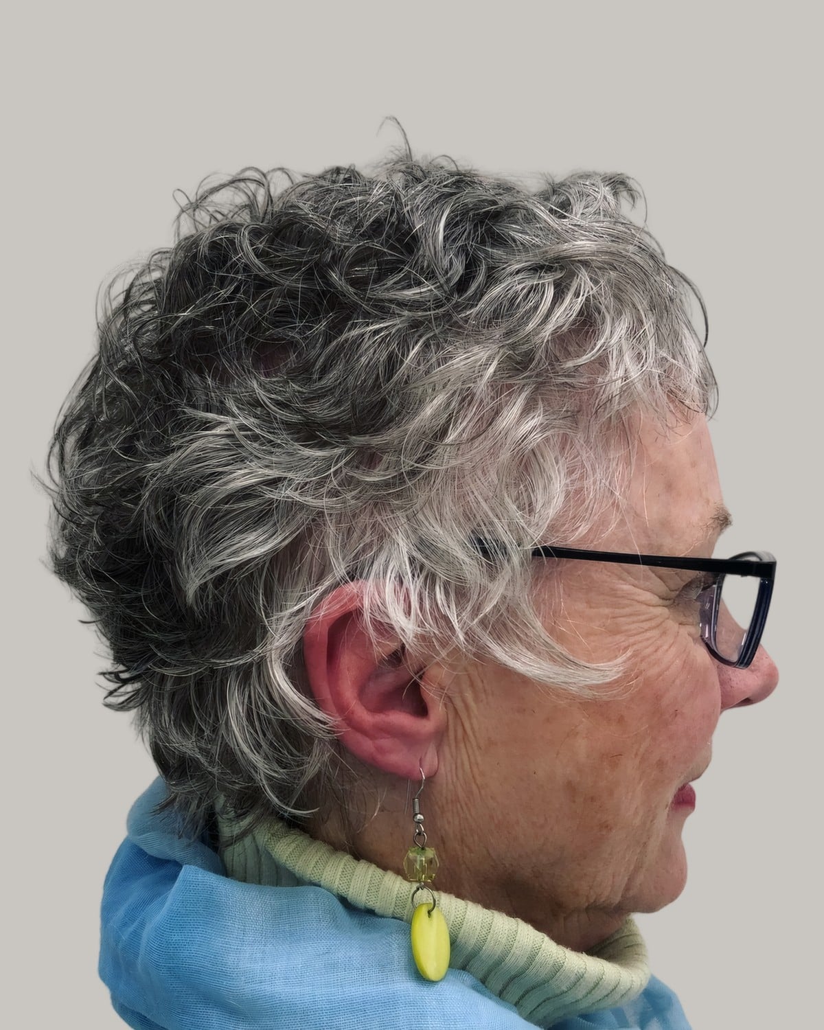 Woman with short salt-and-pepper curls and glasses, seen from the side