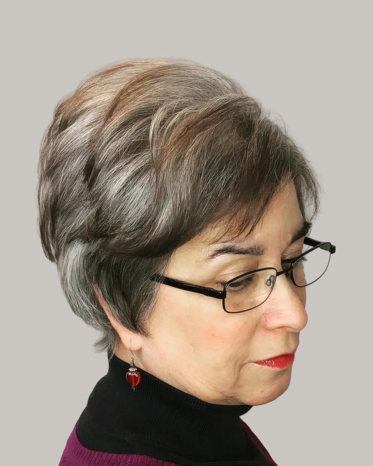 Woman with a gray and brown pixie and thin metal glasses, looking down