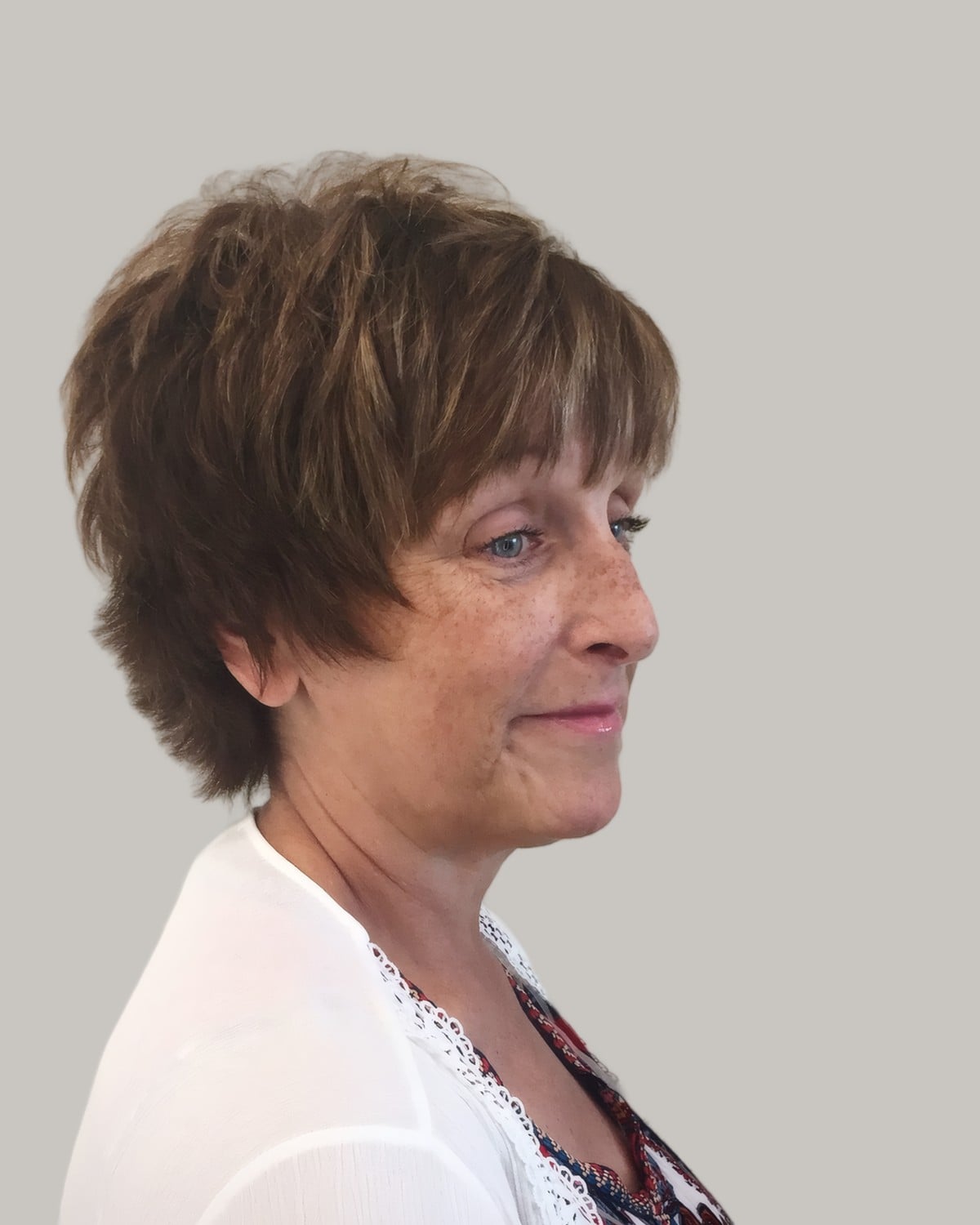 Woman with a long brown layered pixie and a side fringe, seen in profile