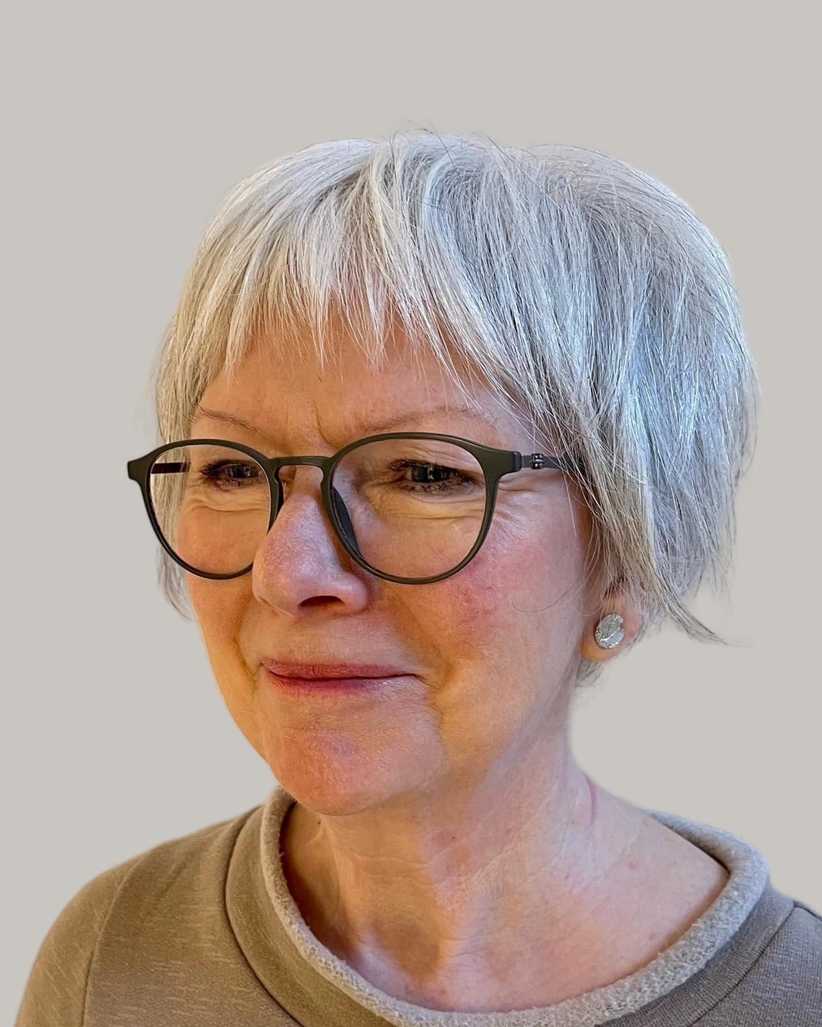 Woman with a white long pixie and dark round glasses, in three-quarter view