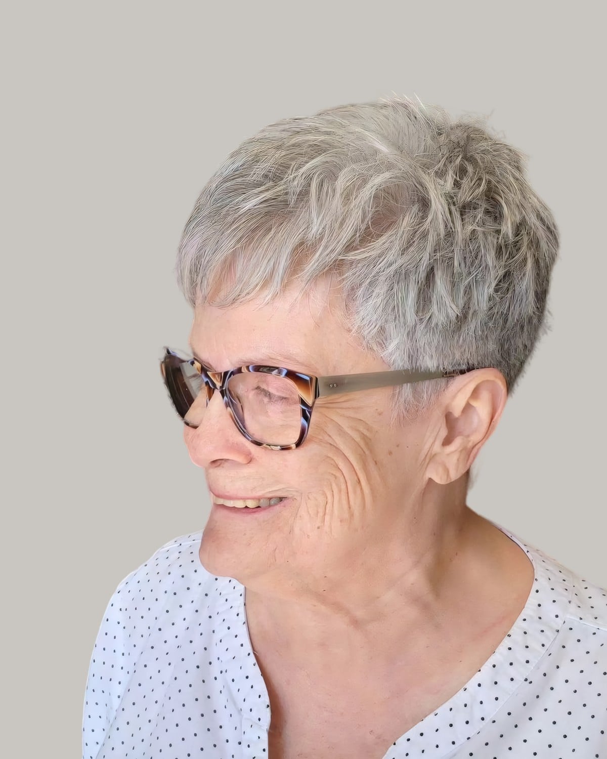 Smiling woman with a silver pixie and tortoiseshell glasses, in three-quarter view