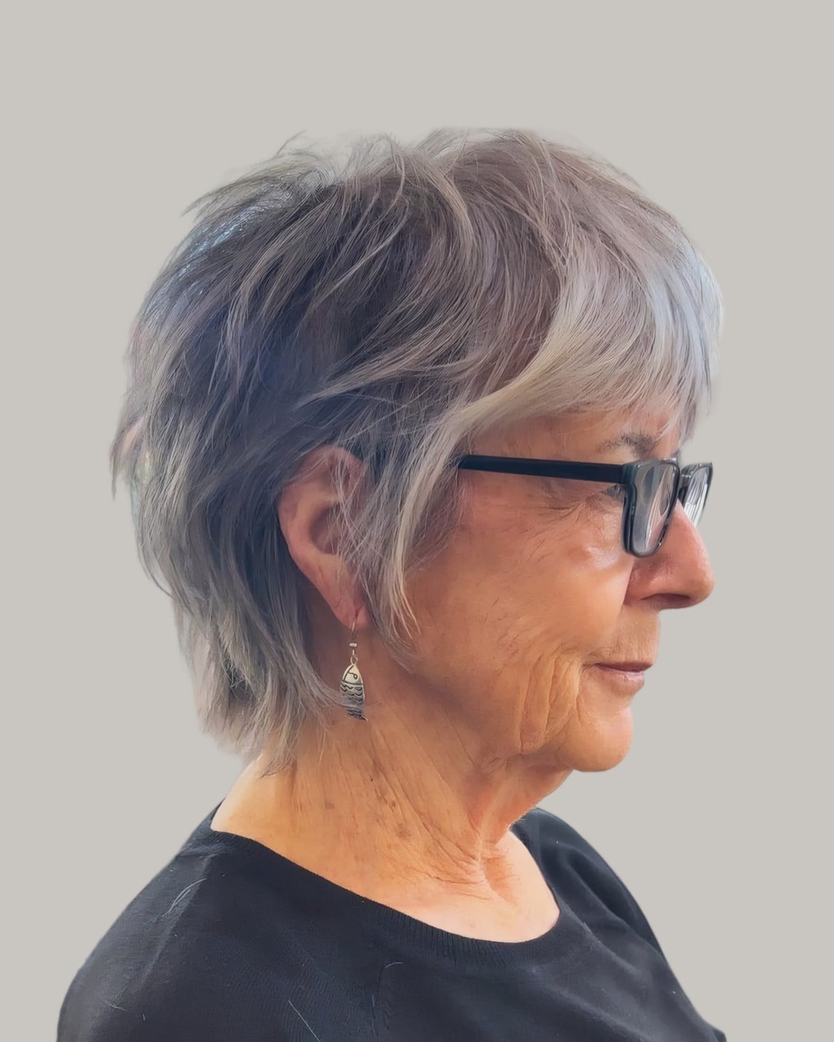 Woman with a gray and silver shag and dark glasses, in profile