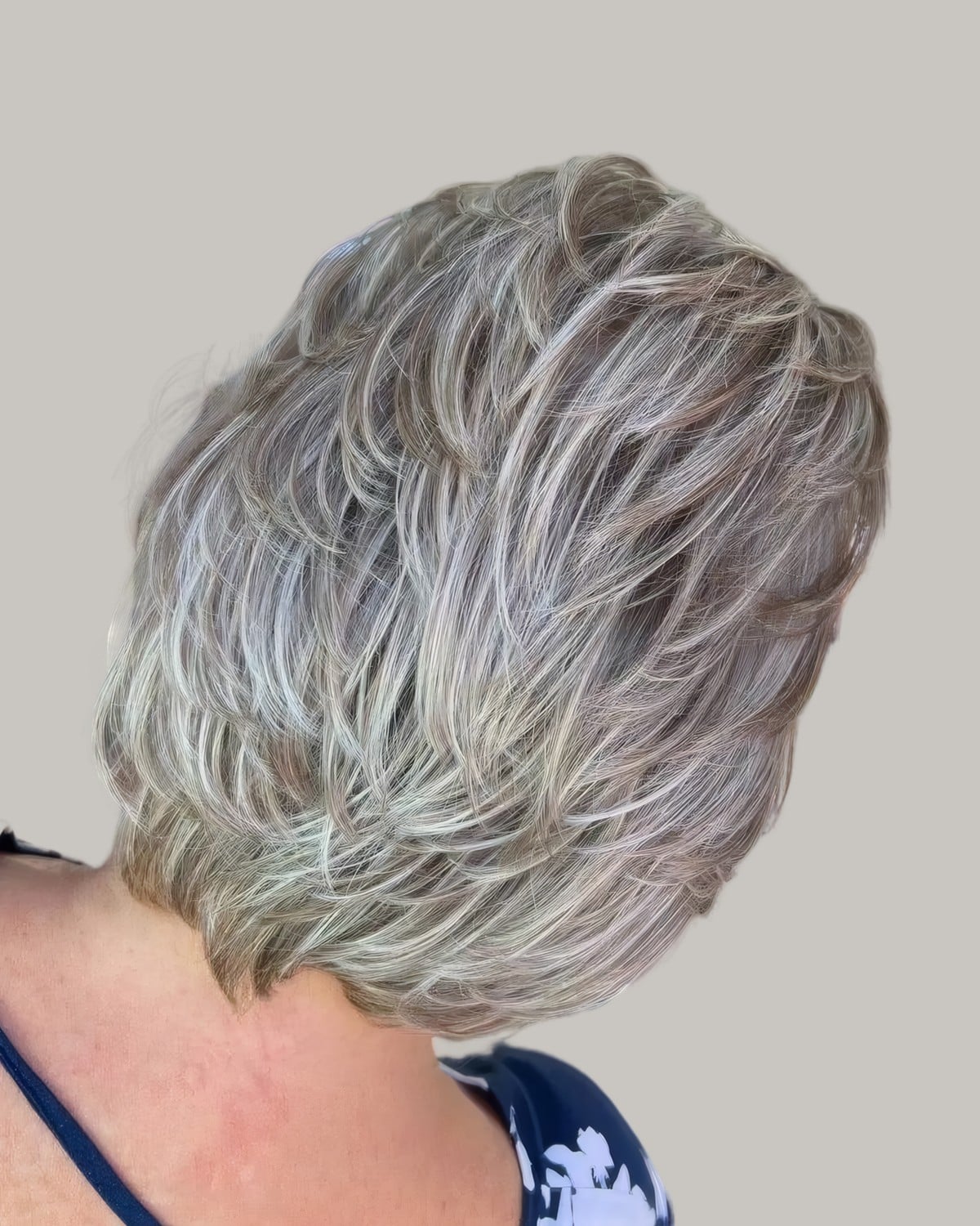 Woman with short, stacked silver-blonde layers, seen from behind