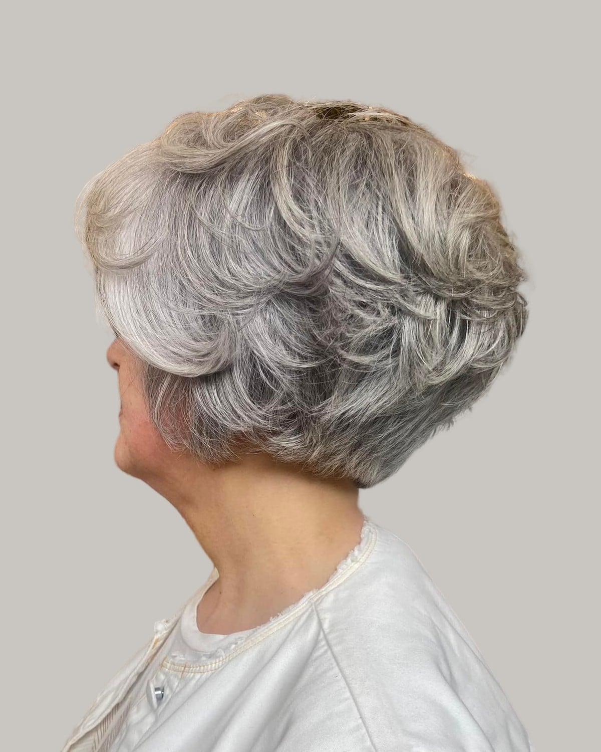 Woman with short, stacked gray layers, seen from the side