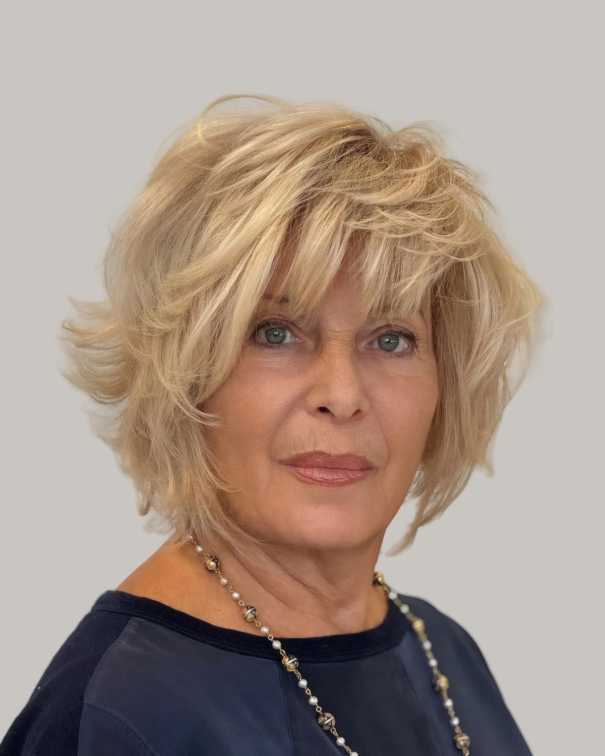 Woman with a tousled blonde shag and a beaded necklace