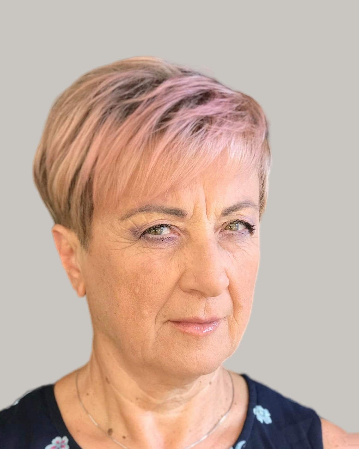 Woman with a rose-blonde textured pixie, in a floral top