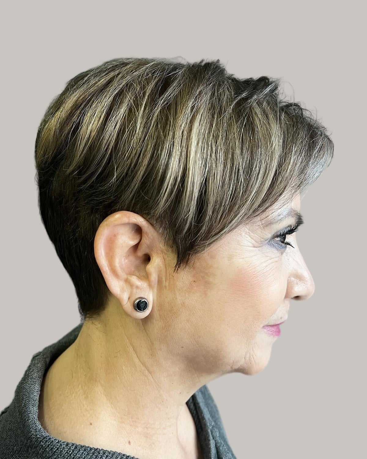 Woman with a dark pixie streaked with silver, seen in profile