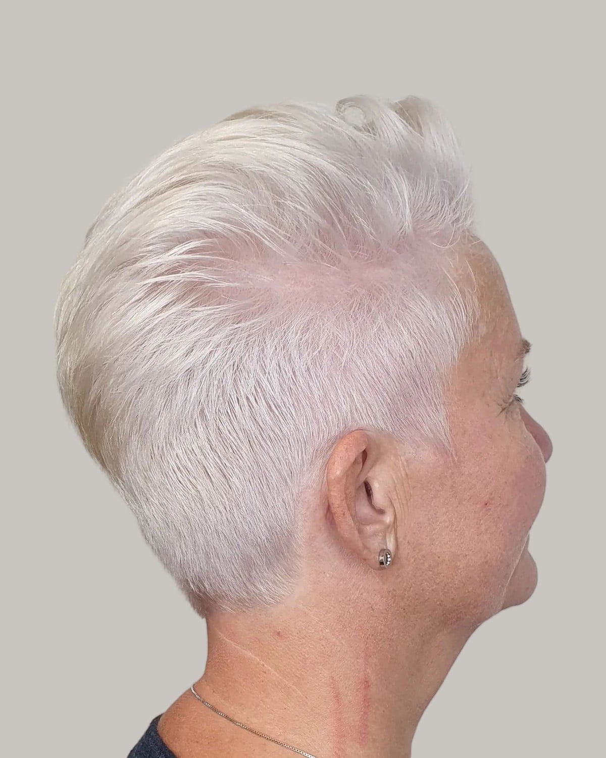Woman with a white pixie and clippered sides, seen in profile
