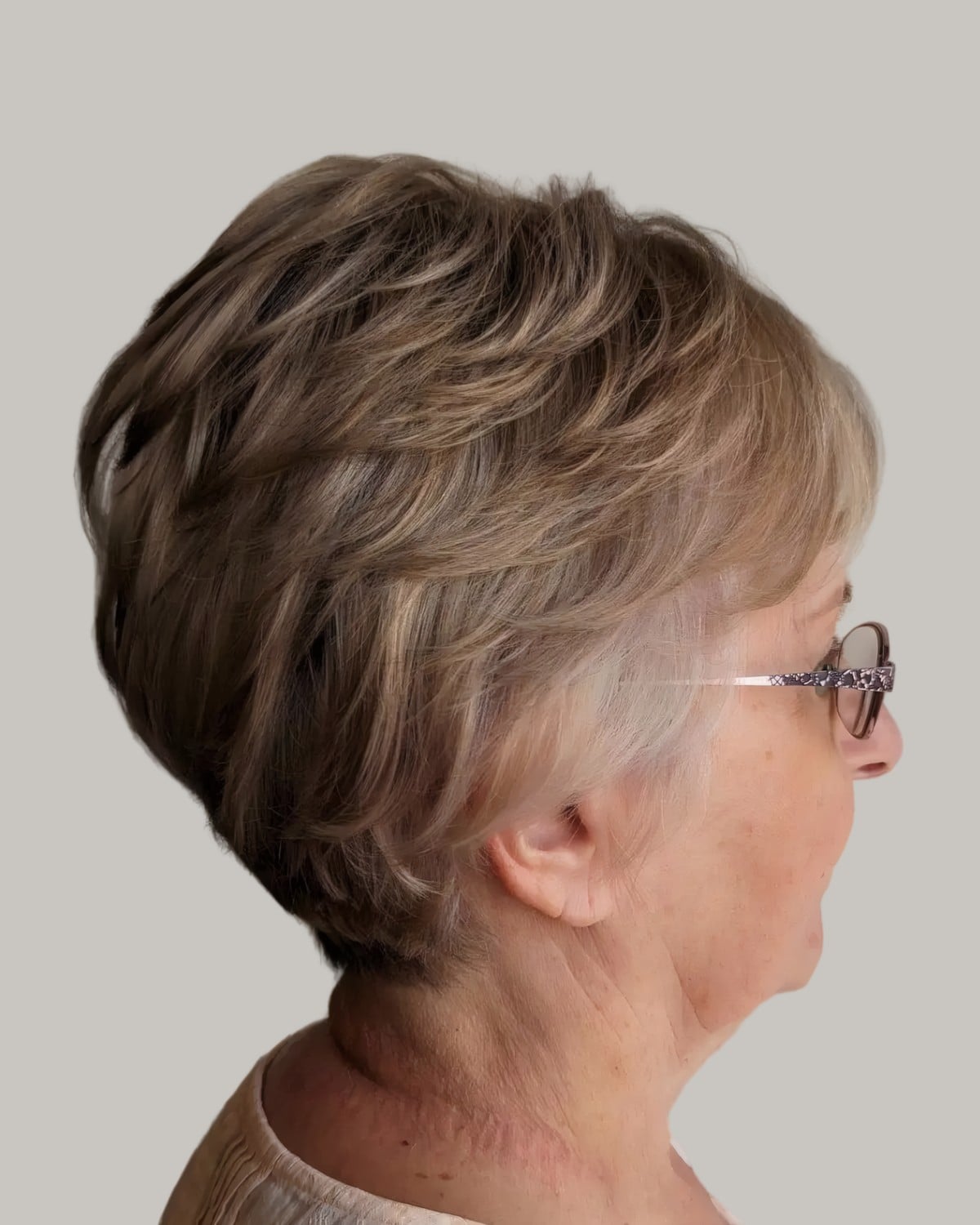 Woman with a full brunette short cut and rimless glasses, seen from behind