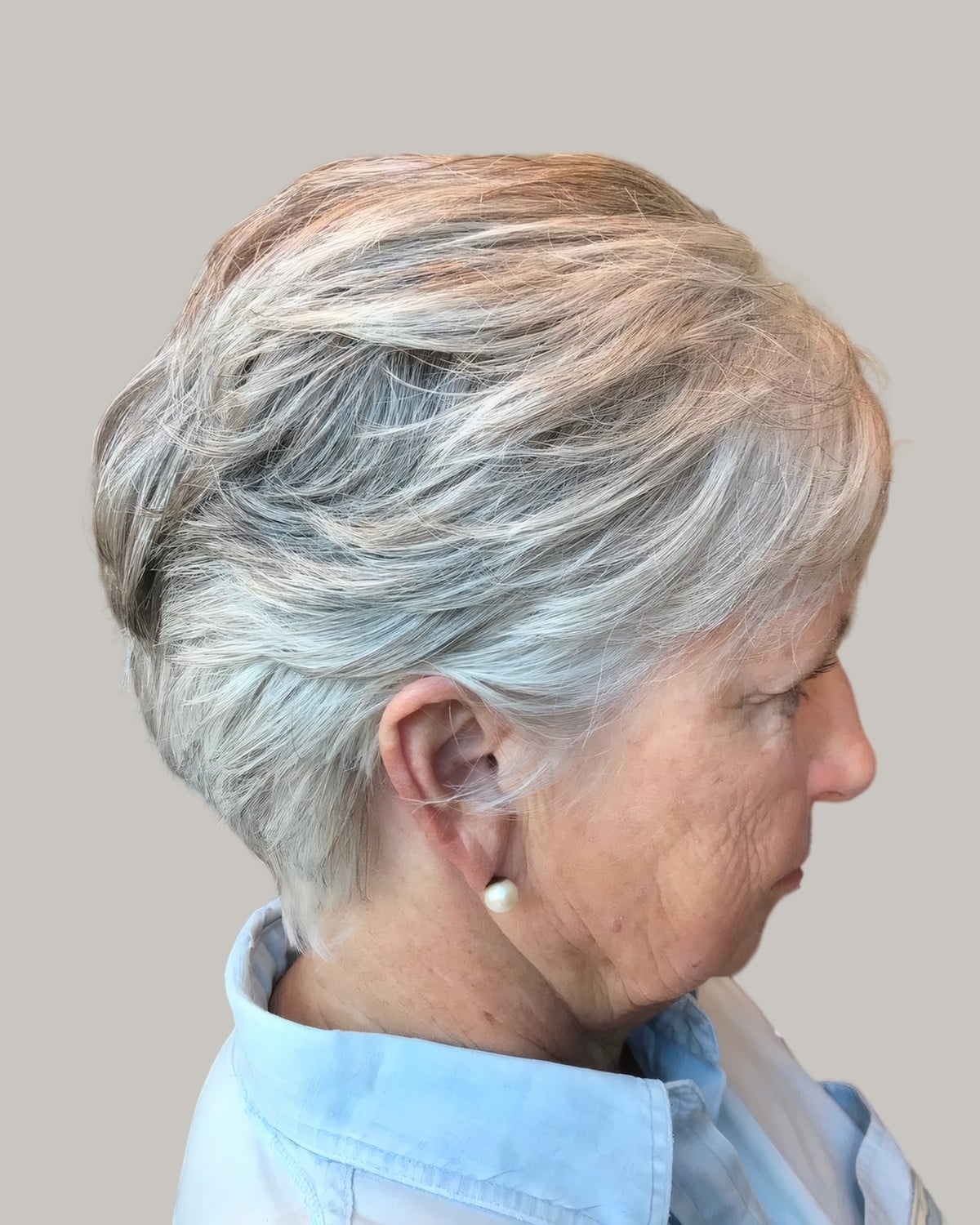 Woman with a silver layered crop and a pearl earring, seen in profile