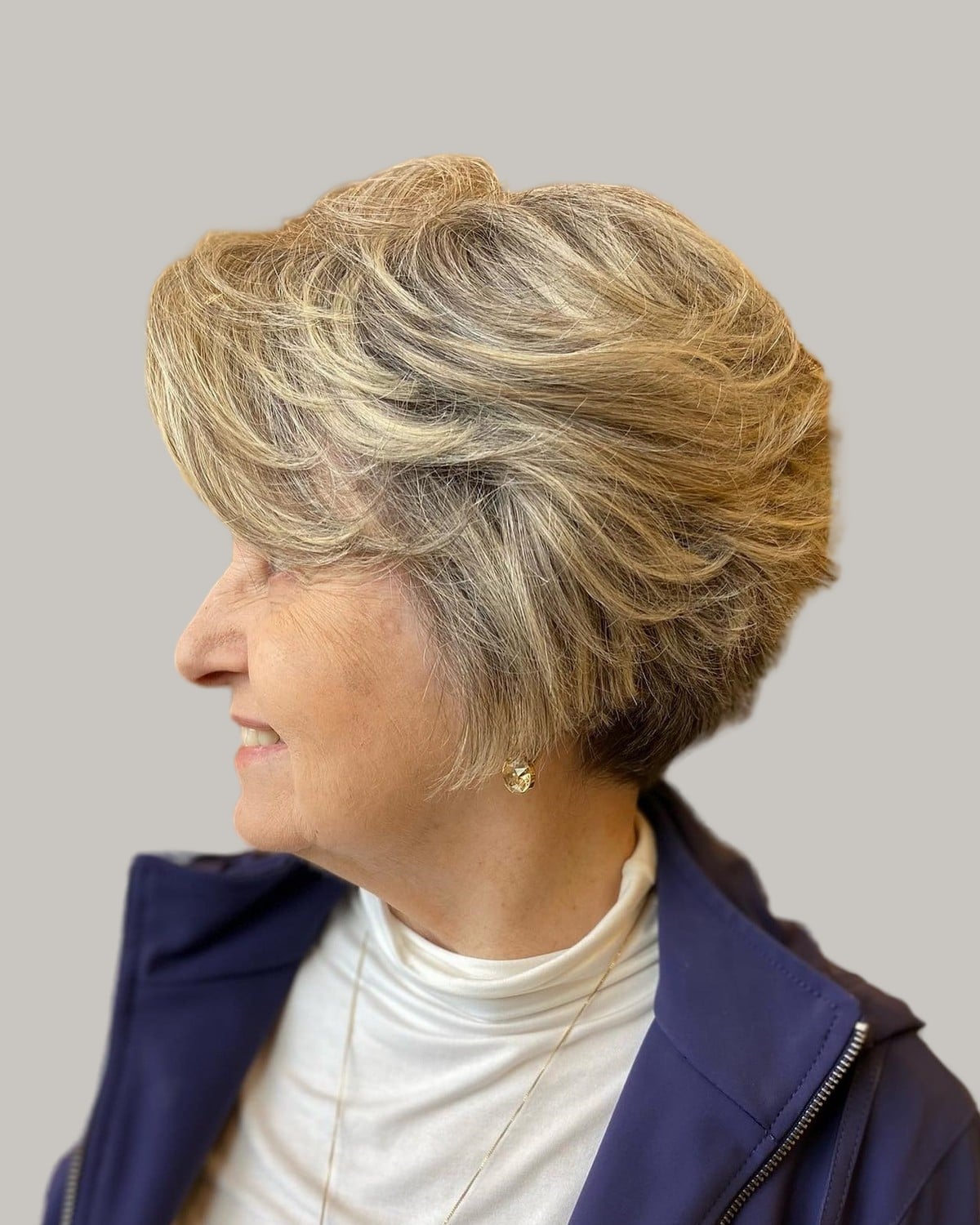 Smiling woman with a short layered crop in sandy blonde, in profile