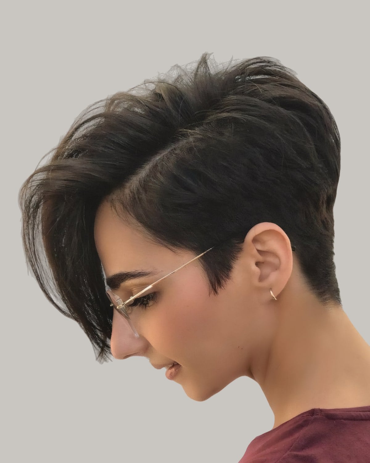 Woman with a dark pixie and one long side bang, looking down