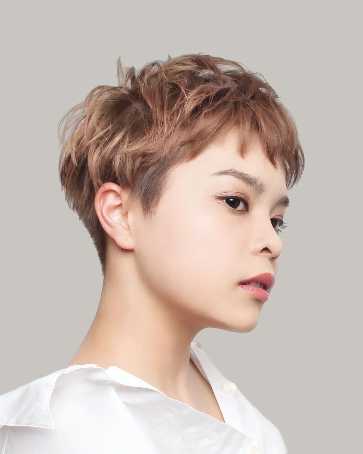 Woman with a copper-brown pixie and choppy baby bangs, in profile