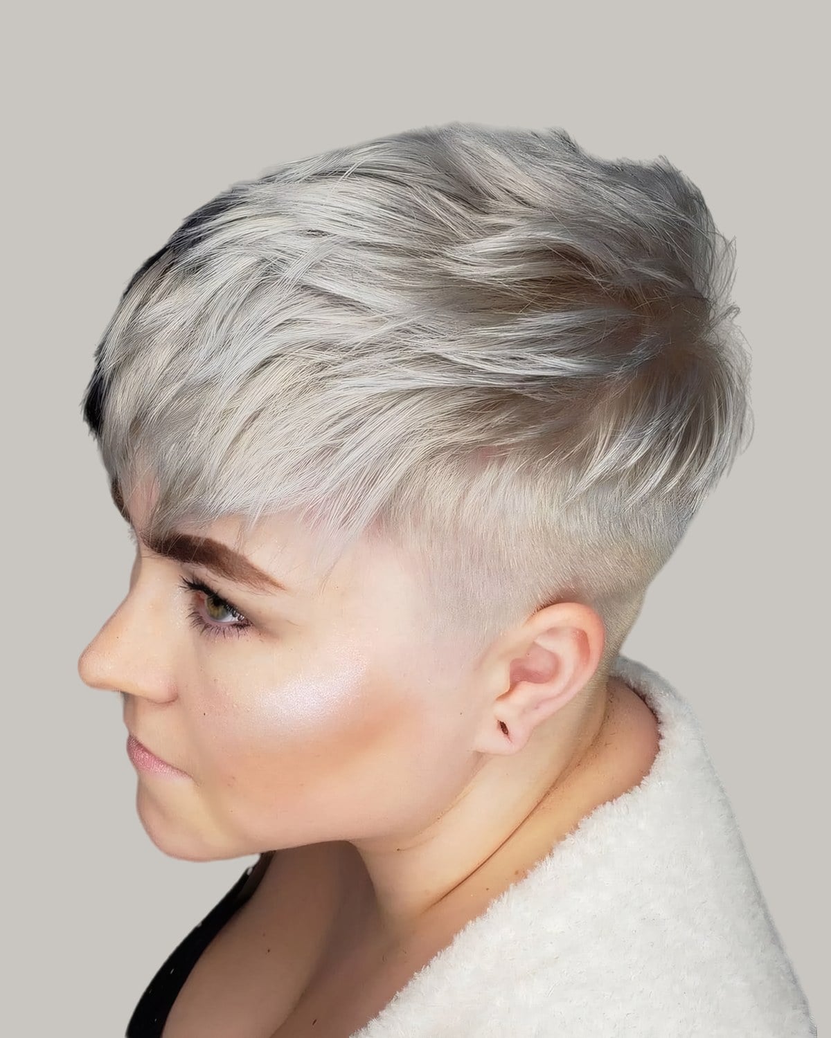 Woman with a platinum undercut pixie, turned to the side